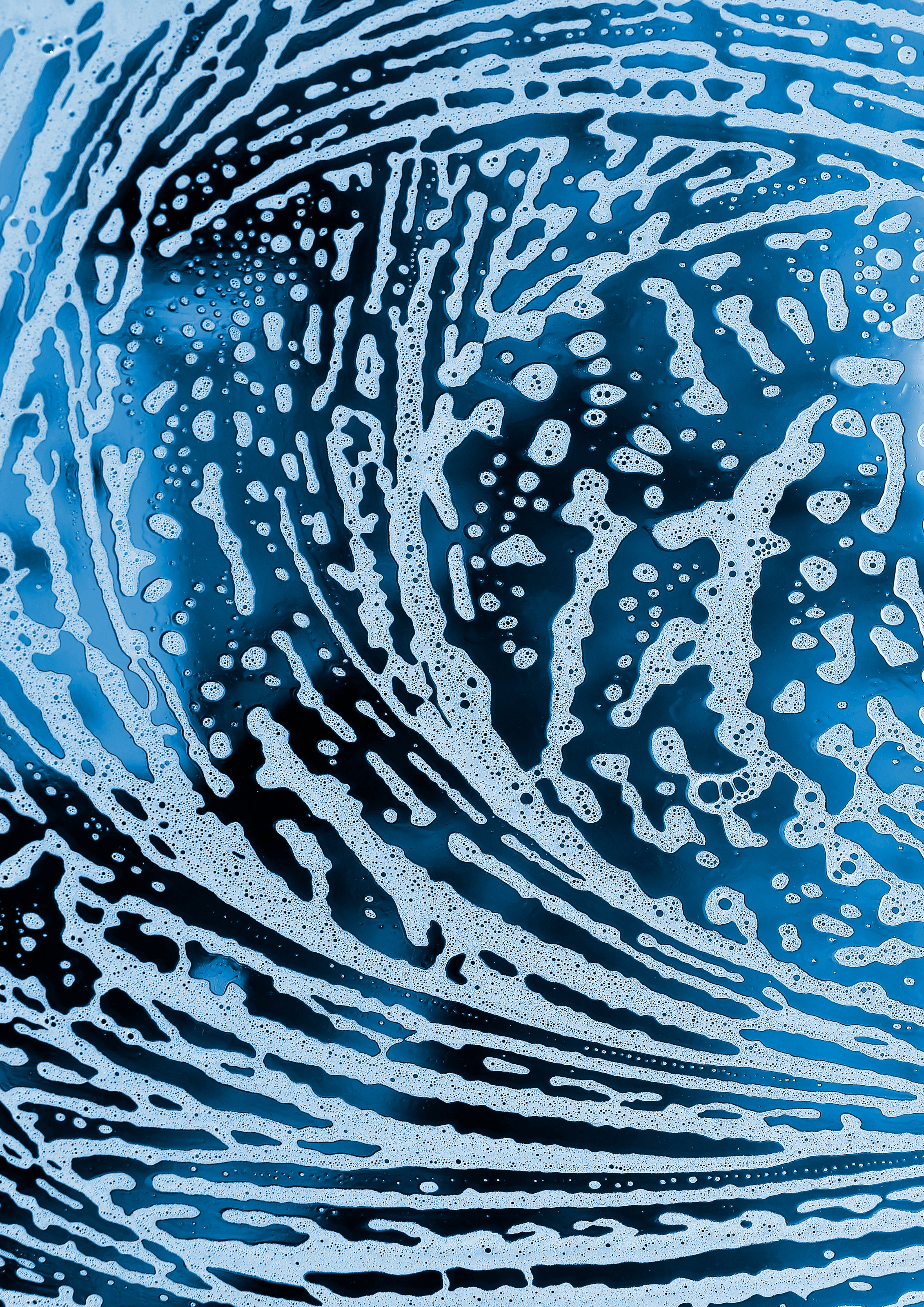 Close-up of soap suds with intricate swirling patterns in shades of blue and white.