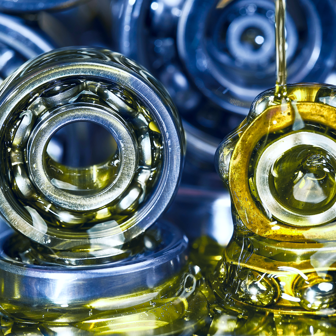 Close-up of multiple ball bearings coated in yellow lubricant, stacked and assembled for machinery or automotive use.