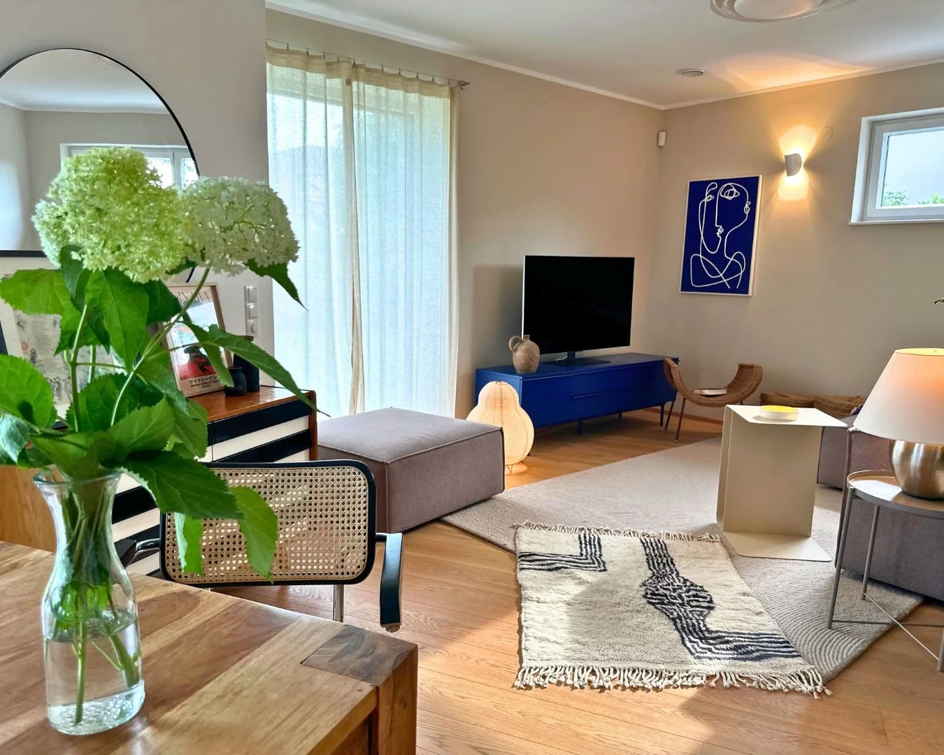 Wohnzimmerdesign mit hellem Holzboden, Naturmaterialien, Geometrie, taupefarbenes Sofa, gelber Metalltisch, marokkanischer Teppich, colorblocking, Erdtöne, Marineblau, Jiri Jiroutek Mid-Century Kommode, tschechisches Design, Freischwinger