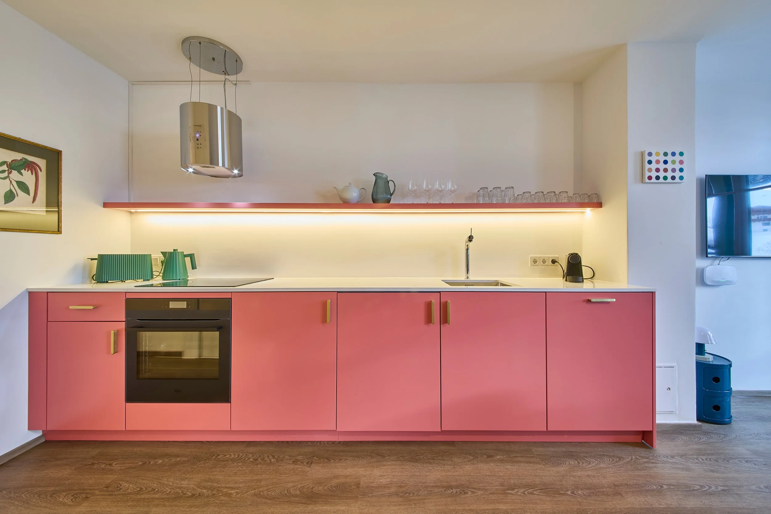 Modernes Küchendesign mit rosa Fronten, offenes Hängeregal aus Edelstahl, grüner Toaster und Wasserkocher, Kunst