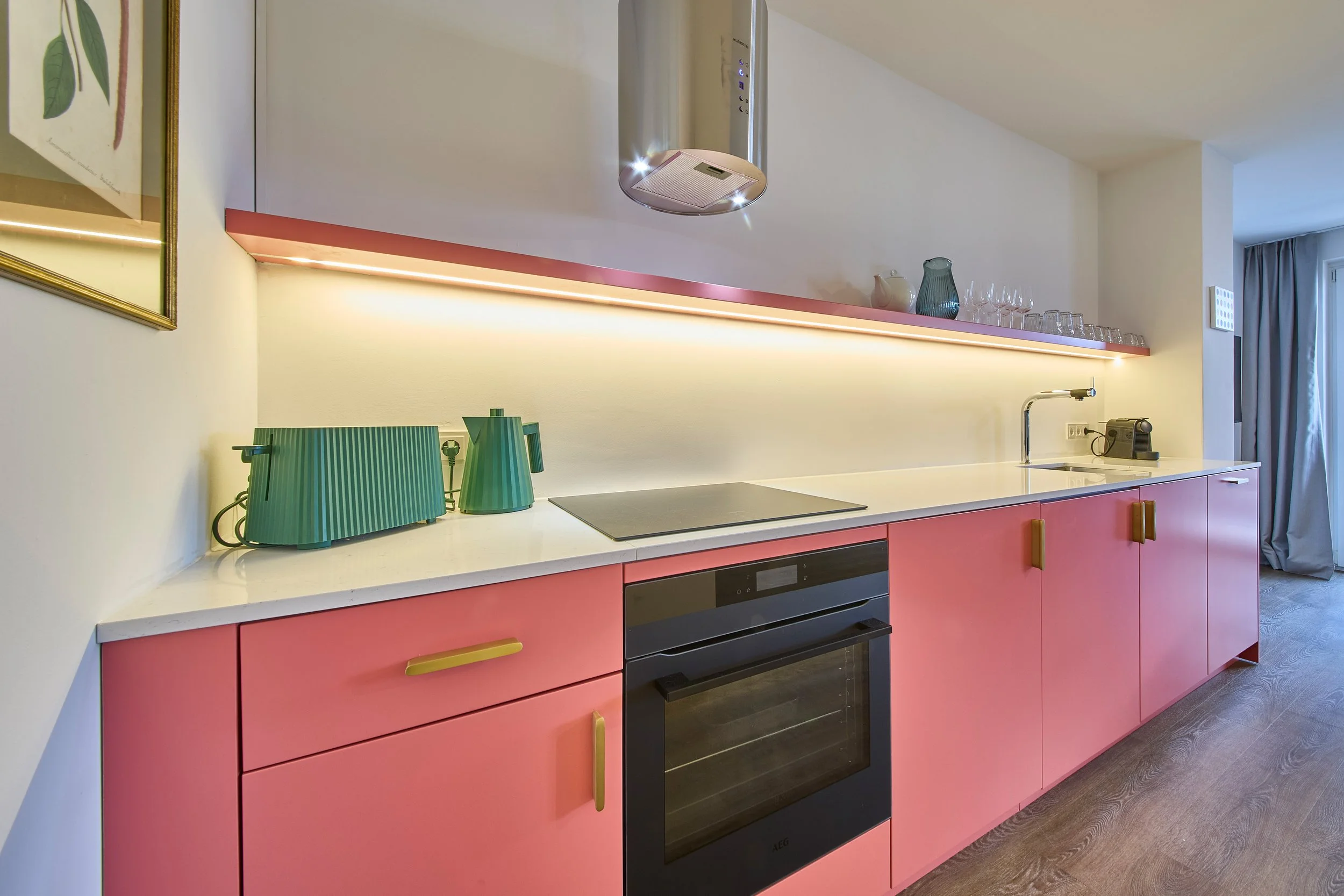 Modernes Küchendesign mit rosa Fronten, offenes Hängeregal aus Edelstahl, grüner Toaster und Wasserkocher, Kunst
