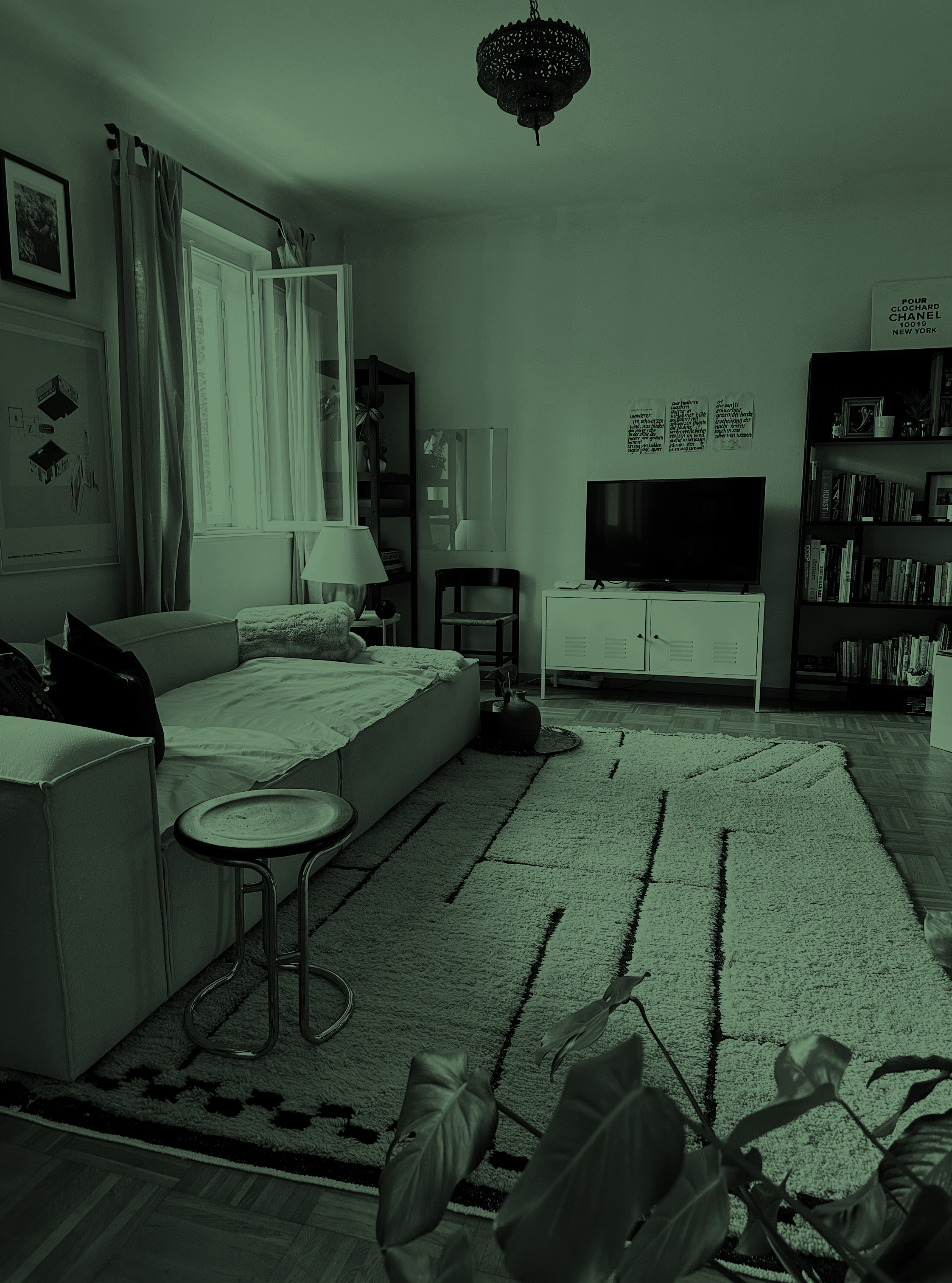 Wohnzimmerdesign mit geradlinigem Sofa, Vintage-Beistelltisch, marokkanischem Beni Ouarain Teppich und Deckenleuchte, Bücherregal und Kunst an den Wänden.