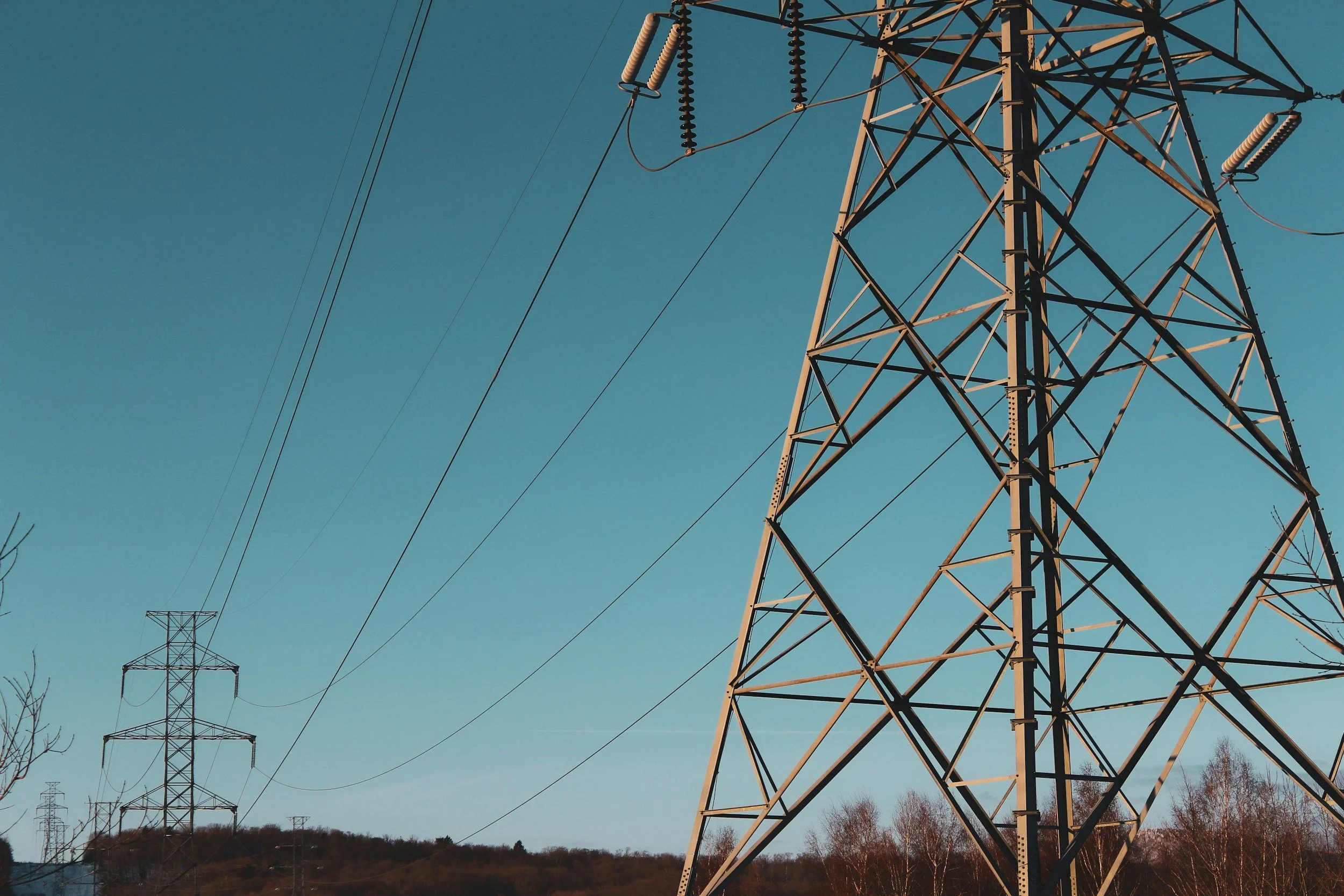 Electric power transmission towers with power lines against a blue sky.
