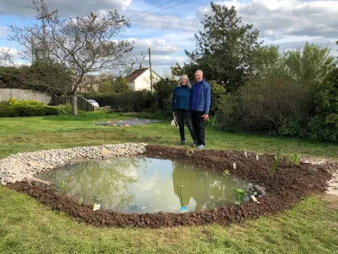 Two of The Nature Gardener's clients stood by their newly build wildlife pond in Somerset.