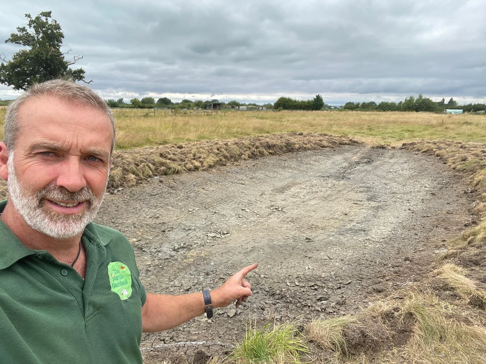 Tony Watt pointing at a newly built scrape in Congresbury, a recent rewilding project he worked on.