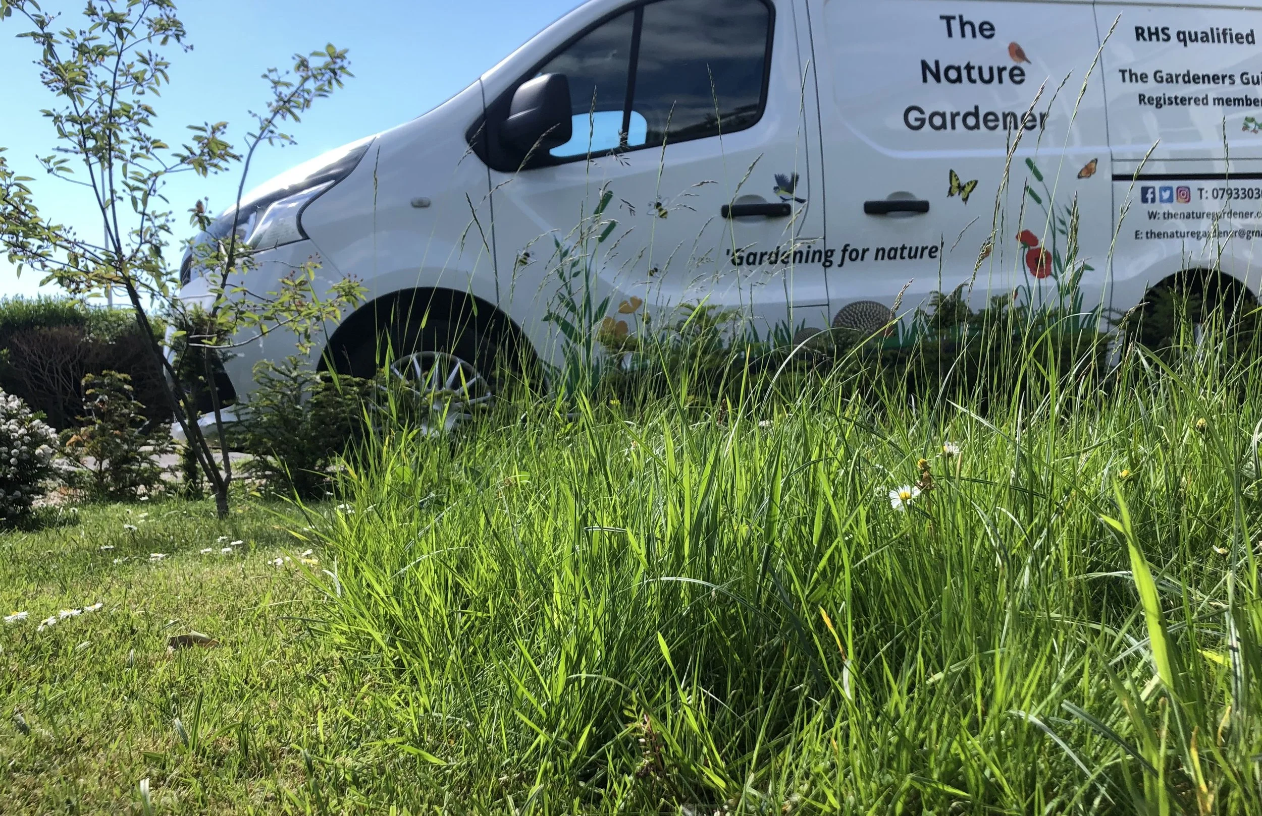 The Nature Gardener van parked next to some long grass.