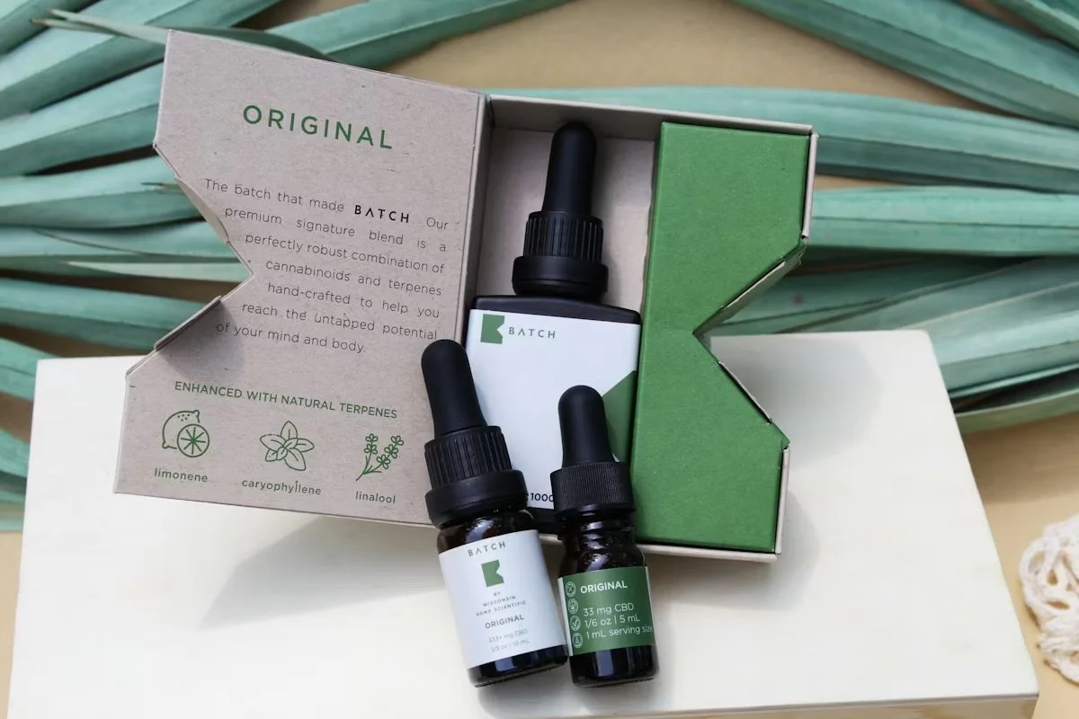 Three bottles inside a green and white box. The box is open to reveal the bottles and a folded informational card.