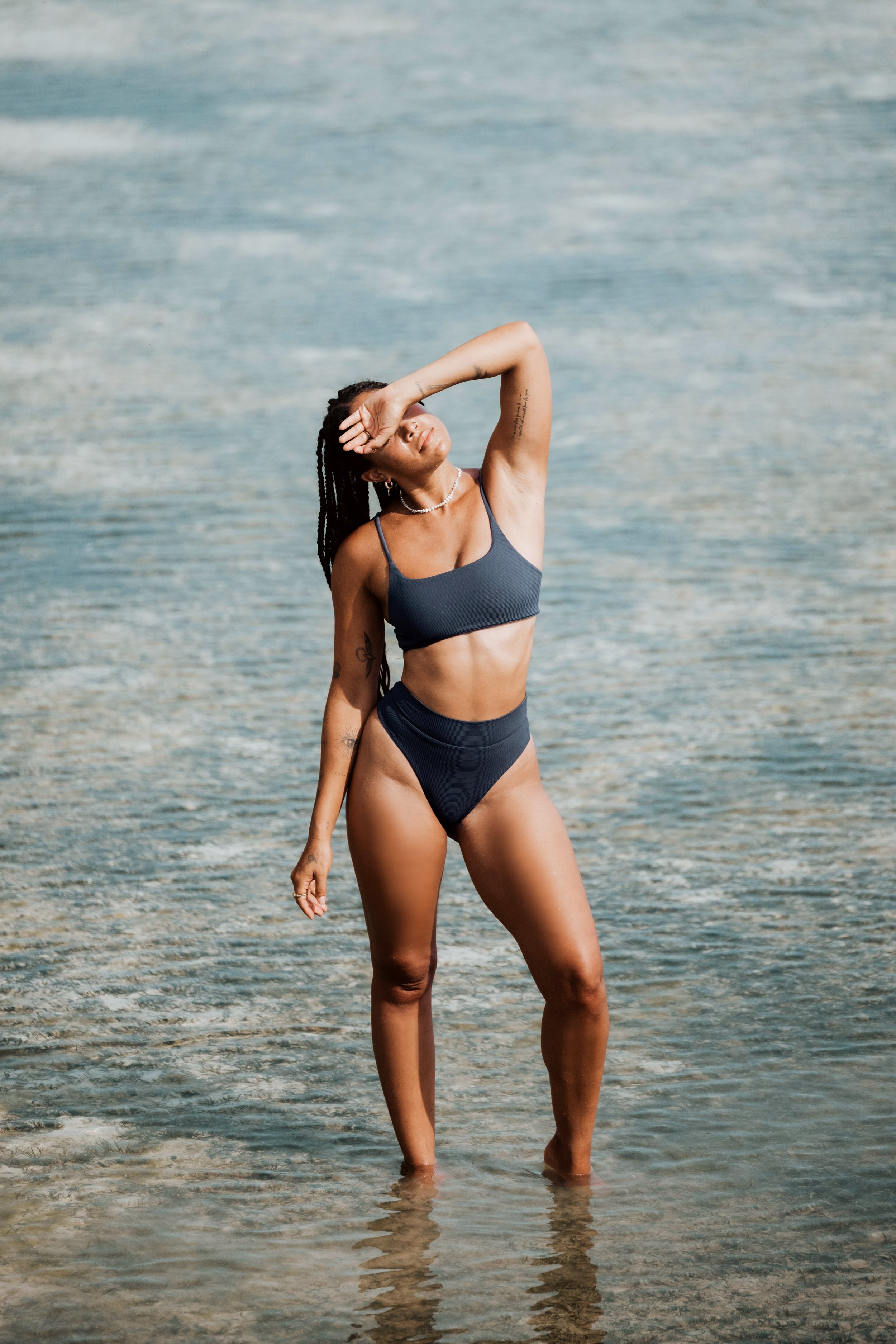 Woman in black bikini standing in shallow water