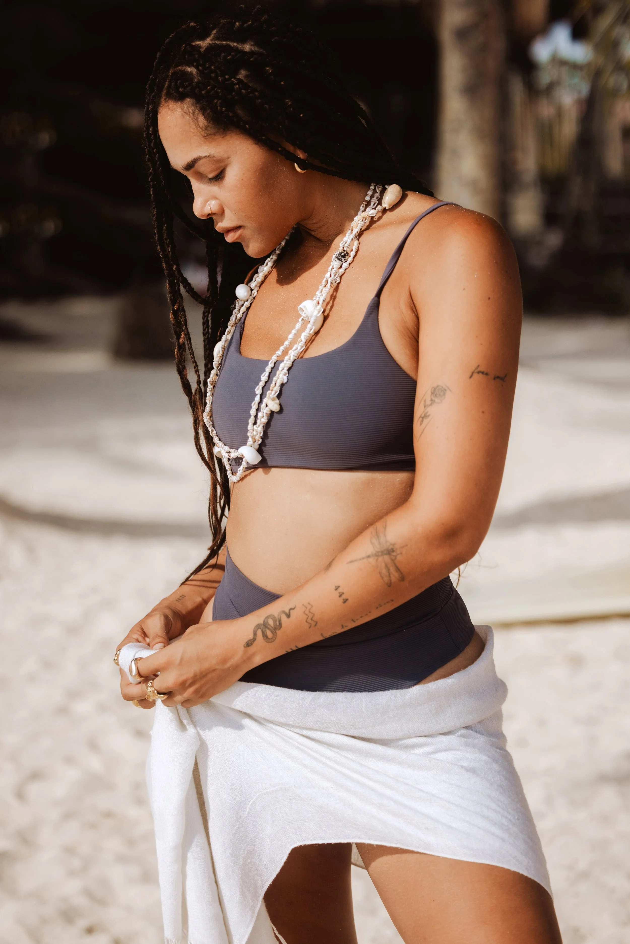 Woman with braids in swimwear and a shell necklace on a beach