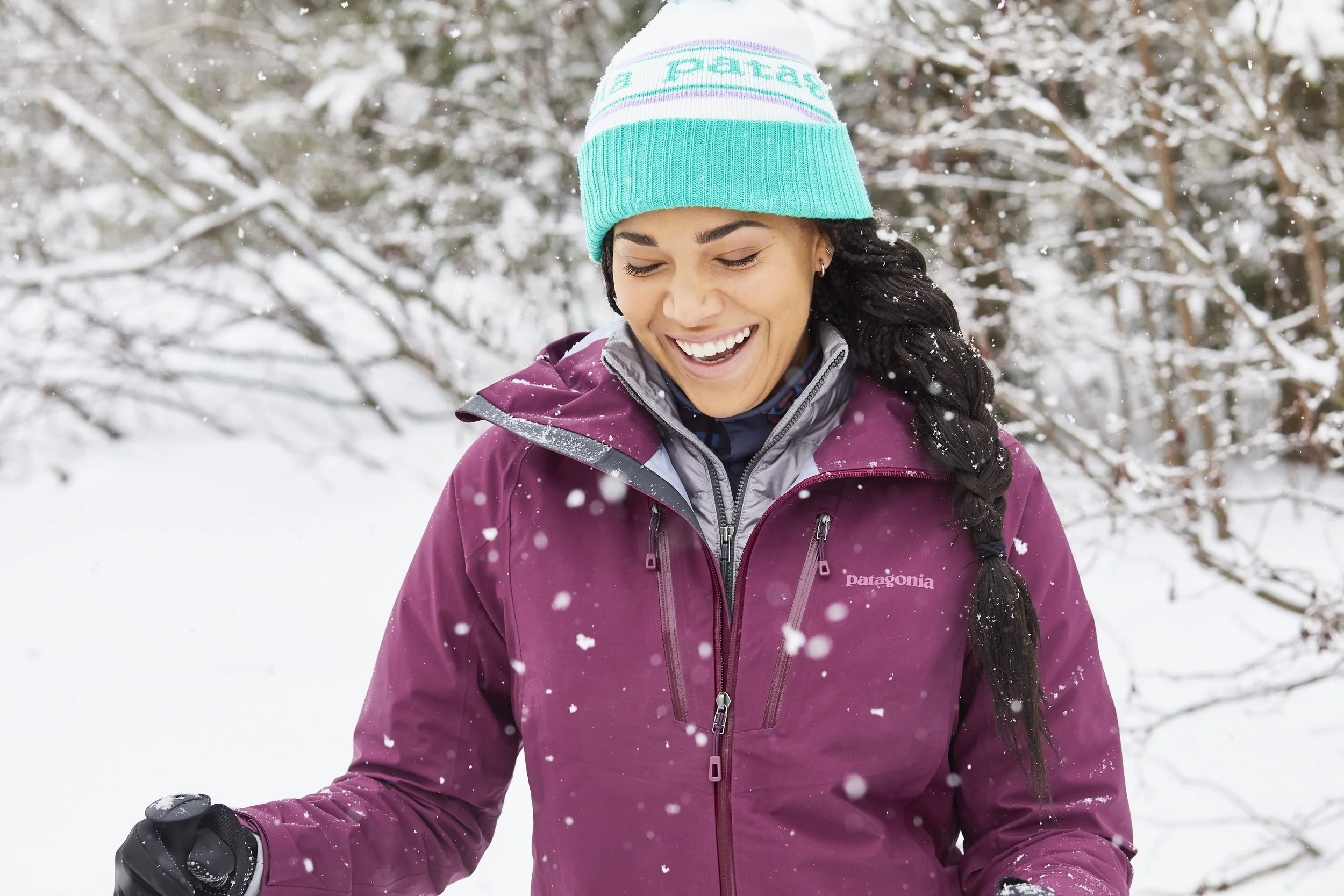 Woman in a snowy landscape wearing a purple jacket and blue beanie