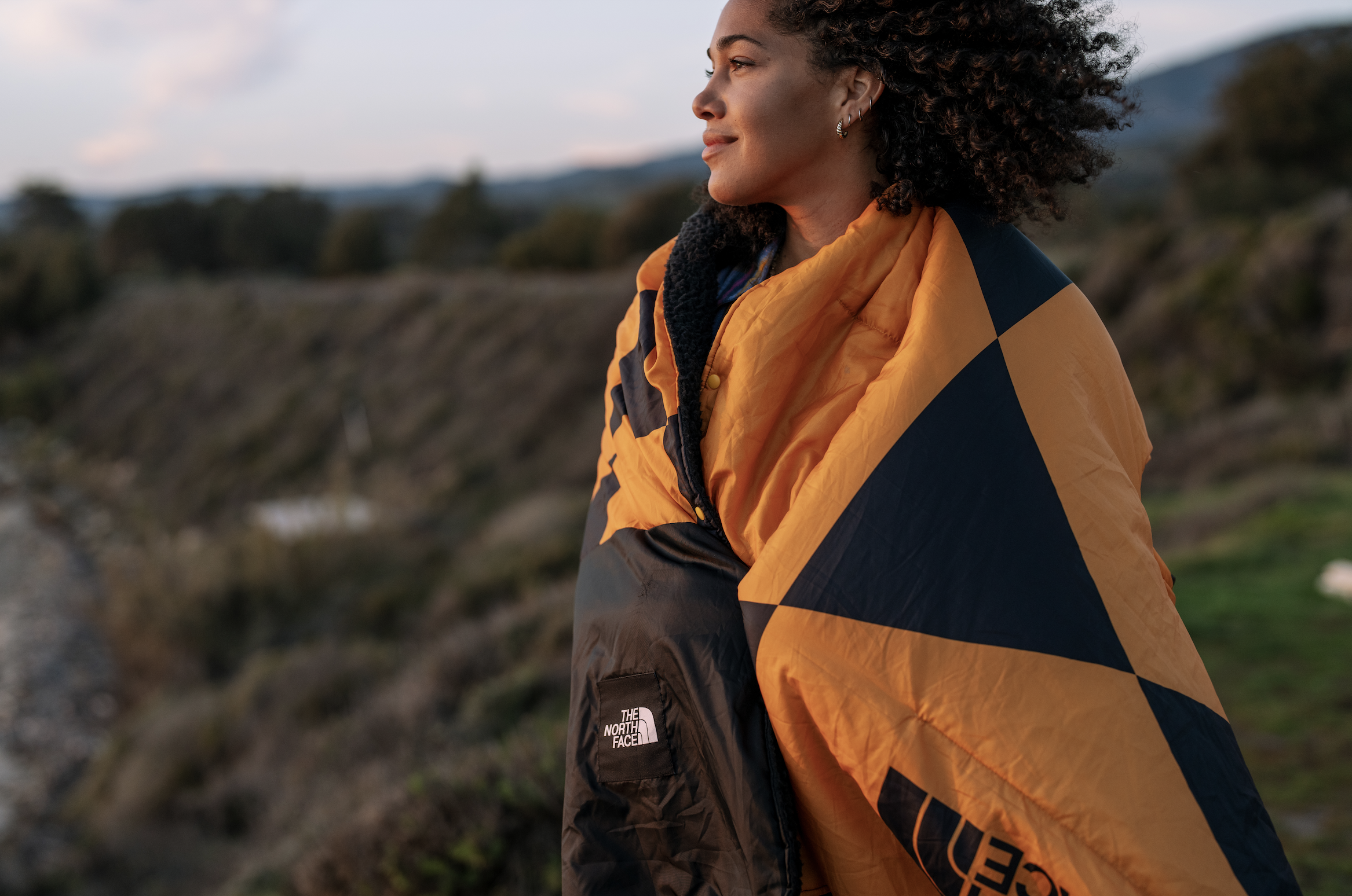 Woman wrapped in The North Face jacket looking at landscape