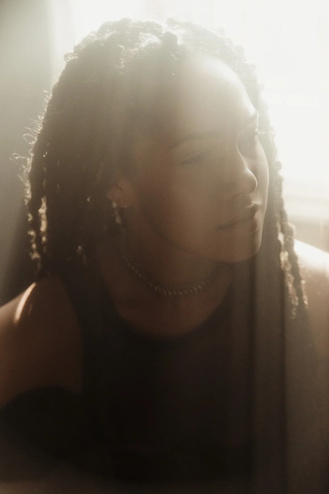 Portrait of a person with braided hair in soft lighting.