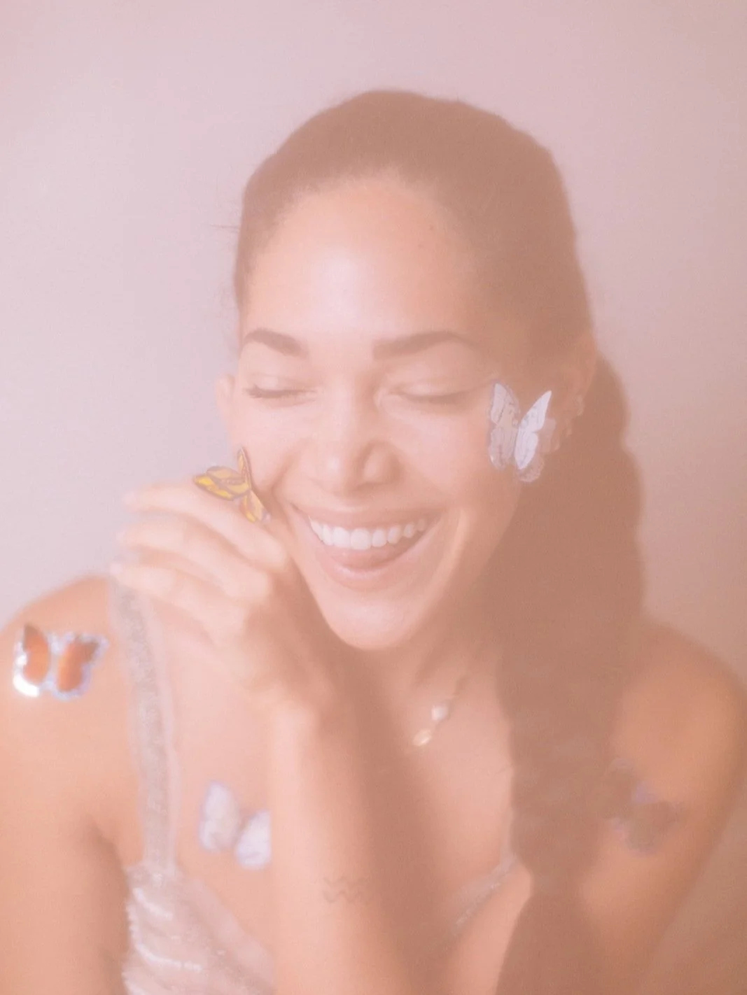 Smiling woman with butterflies on her body in soft focus.