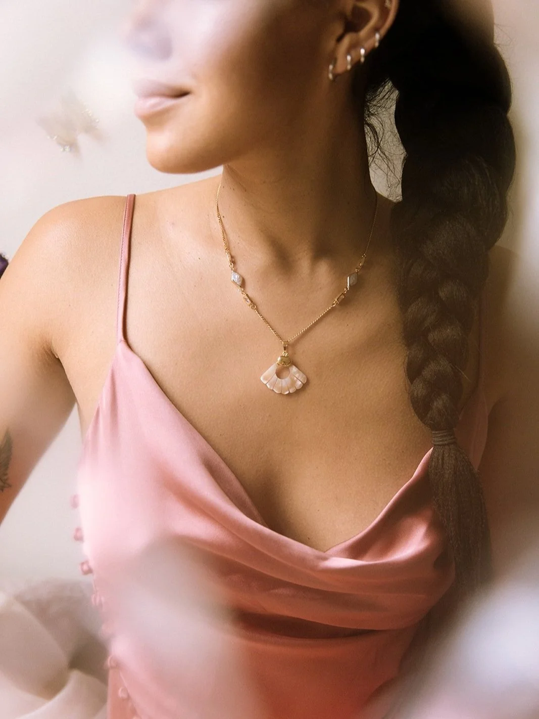Woman in a pink satin dress with a gold necklace and braided hair