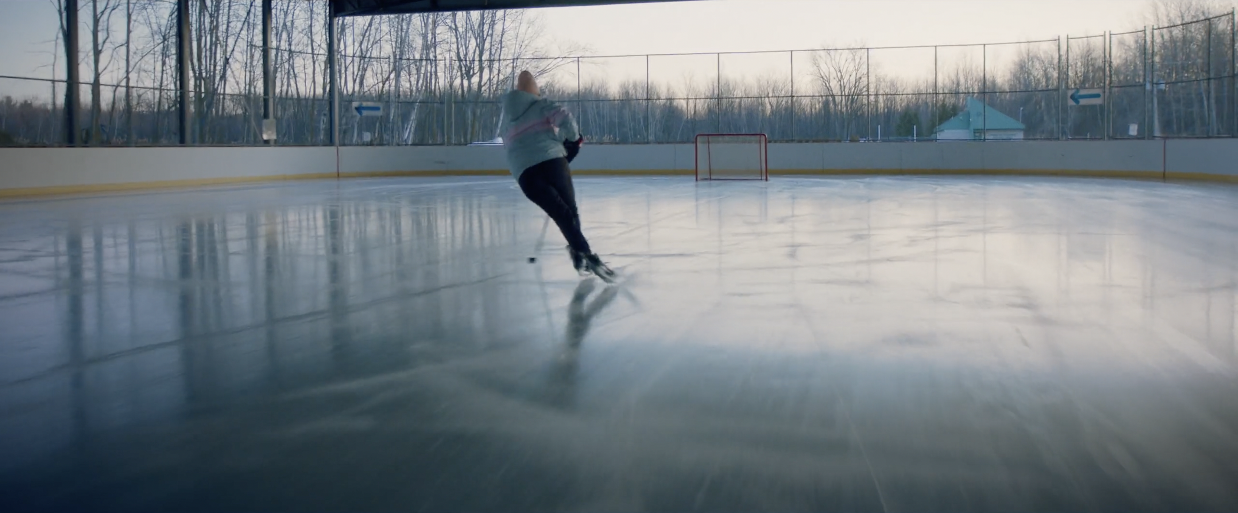 Person playing hockey alone on an outdoor rink