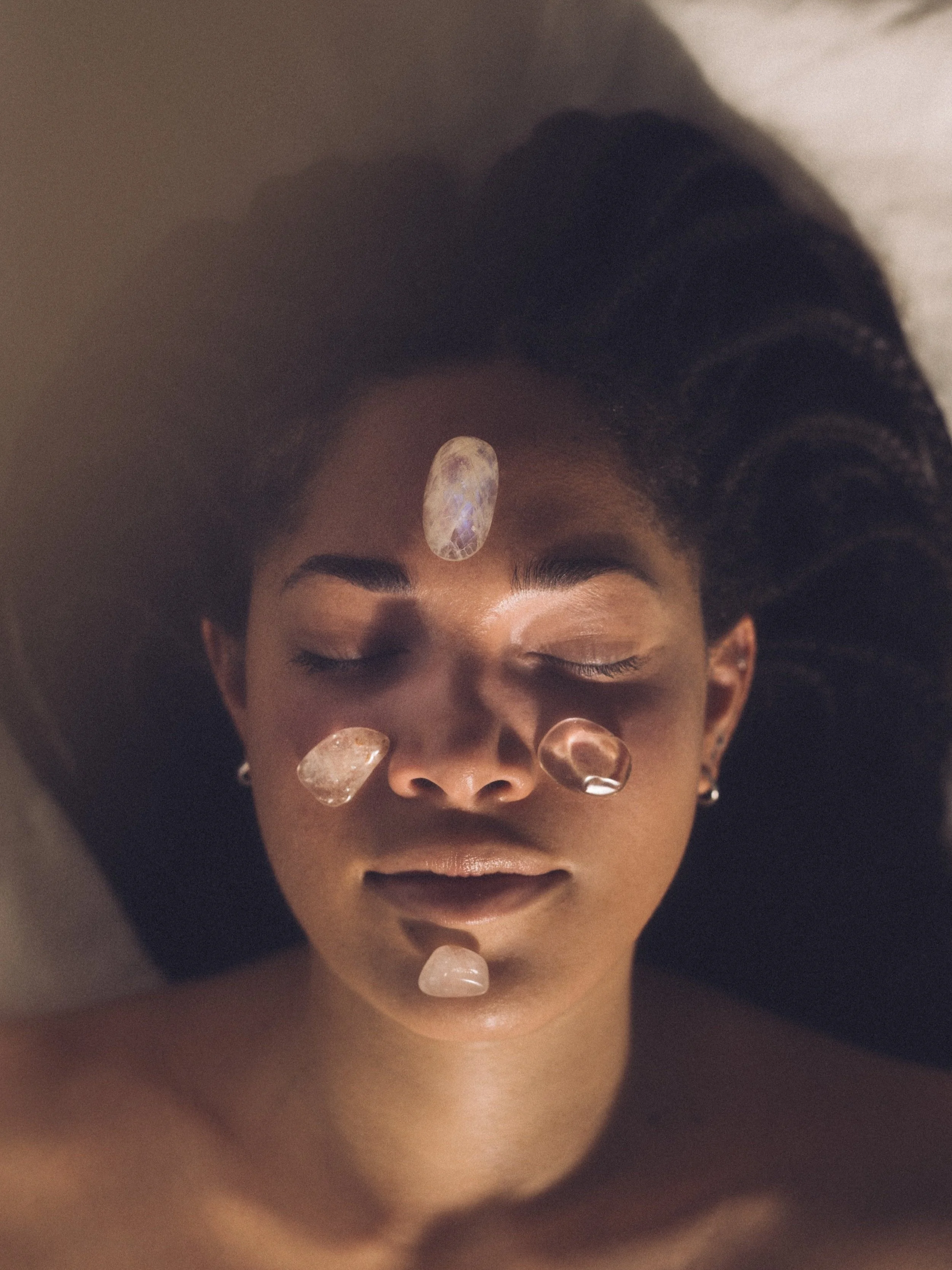 Person lying down with crystal healing stones on face