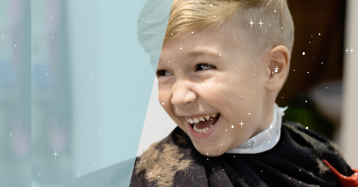 A young boy with blonde hair laughing joyfully, likely at a barber shop after getting a haircut.