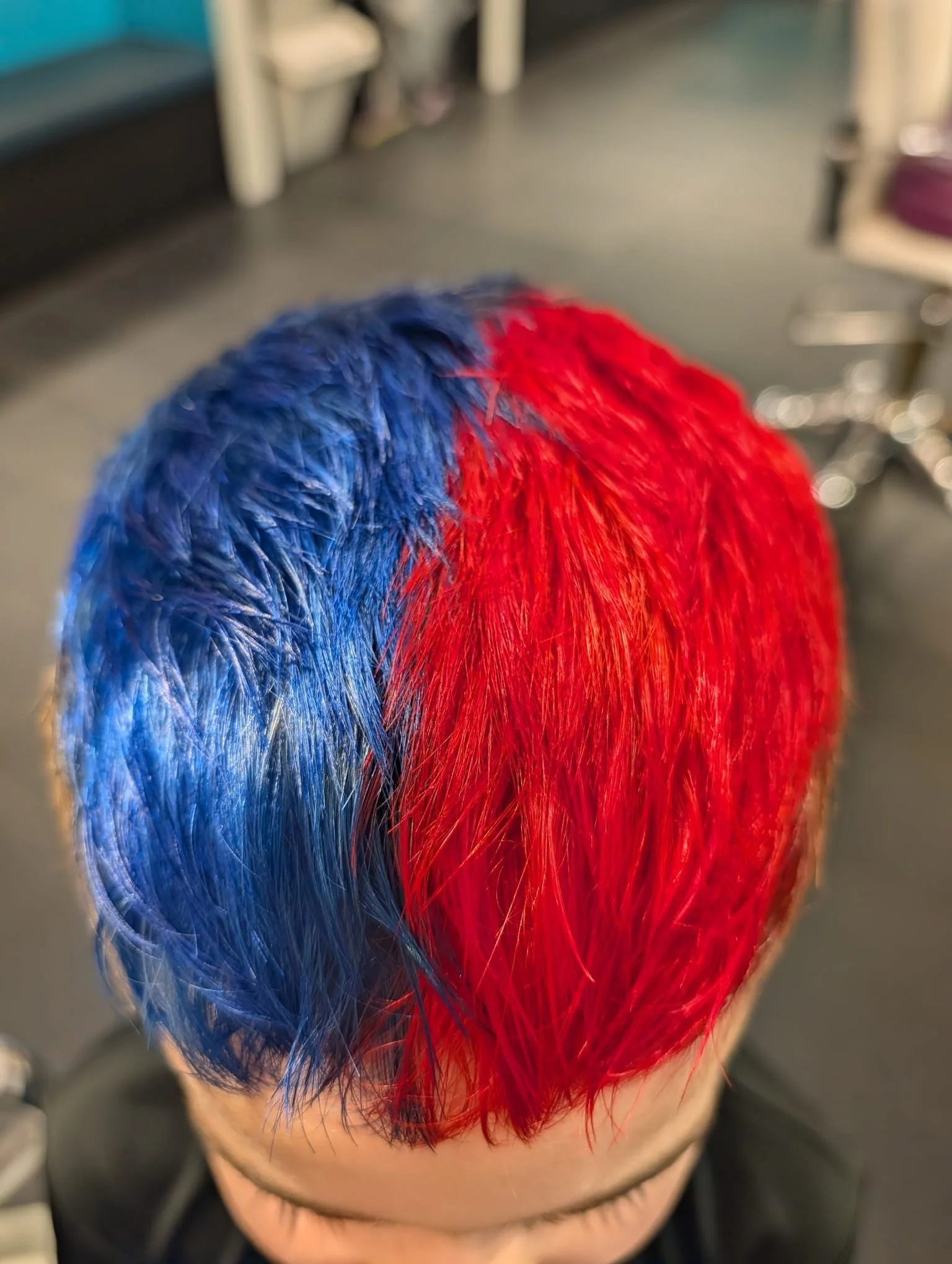 Close-up of hair dyed red and blue on top of a person's head.