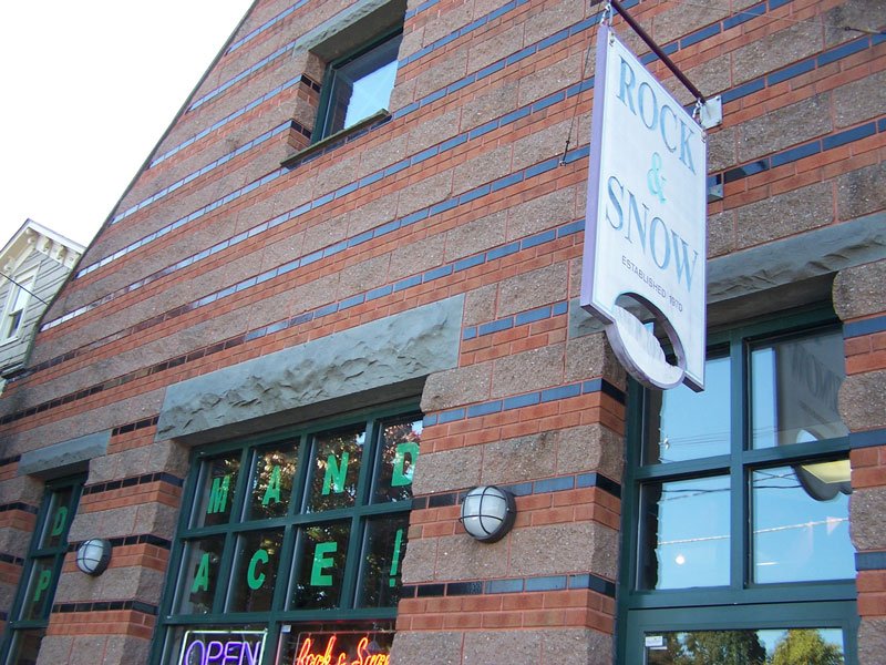 Brick building with a sign that reads "Rock & Snow, Established 1893" and a window display with the words "Hand Made" and an open sign.