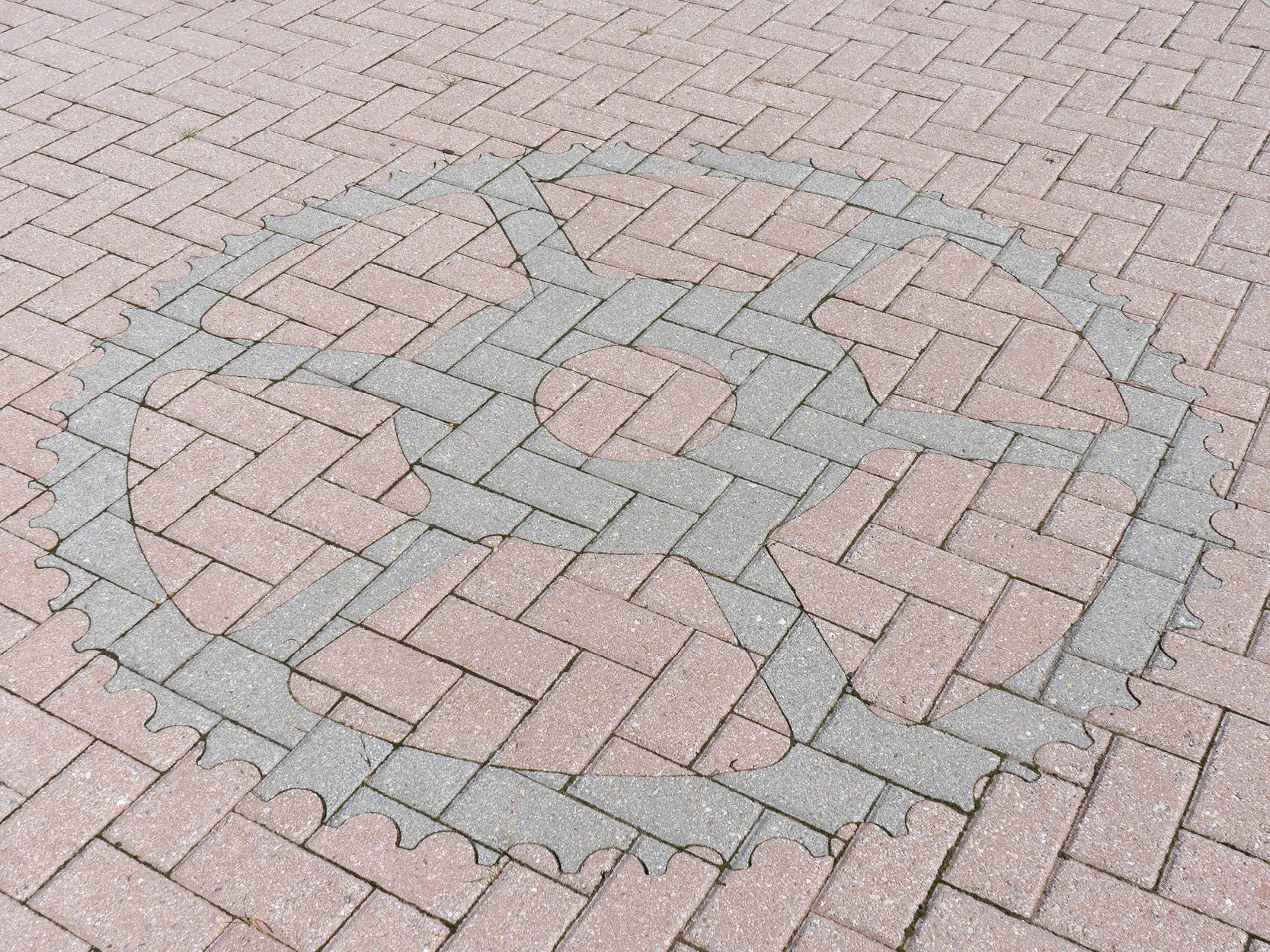 Brick pavement with a border outlining a chess pawn, converting the pattern of the bricks into the shape of a chess piece.