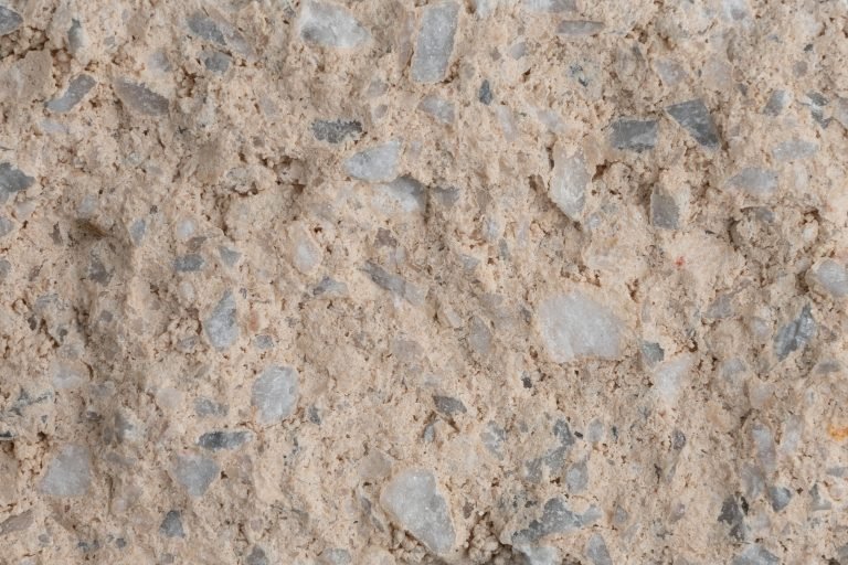 Close-up of beige dirt or sand with small gray and white rocks.