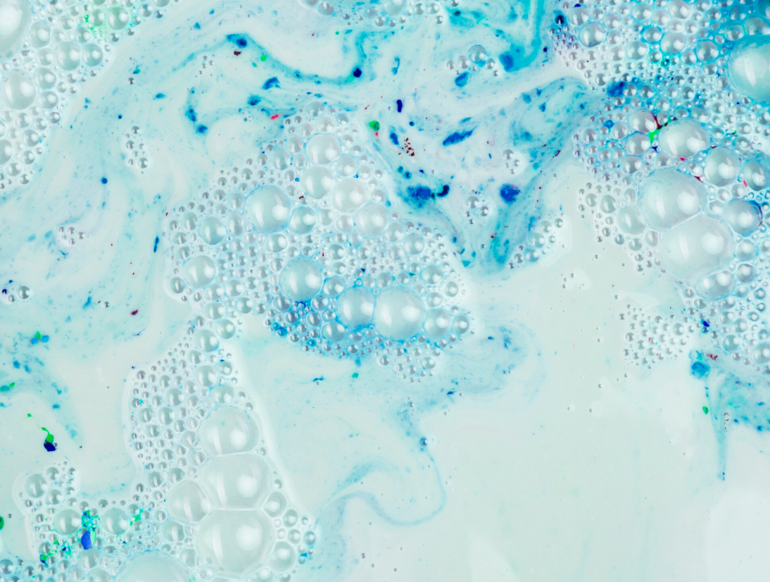 Close-up of soap bubbles floating in a mixture of blue and white liquid.