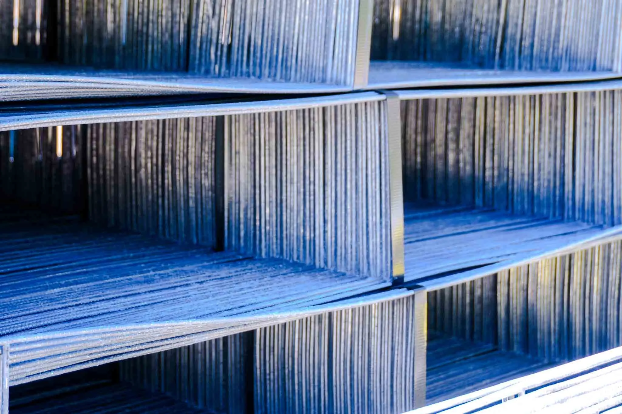 Stacks of metal rails arranged on shelves in a warehouse.