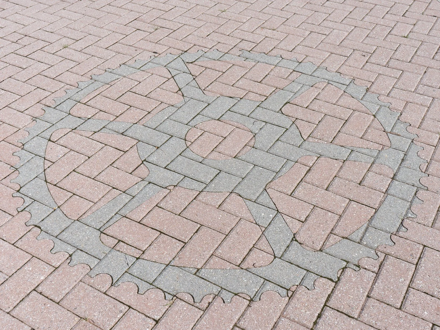 A brick sidewalk with an outline of a chess rook and king outlined in gray bricks.