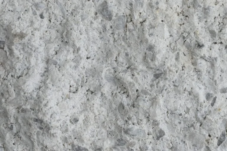 Close-up of a rough, white, textured concrete or stone surface.