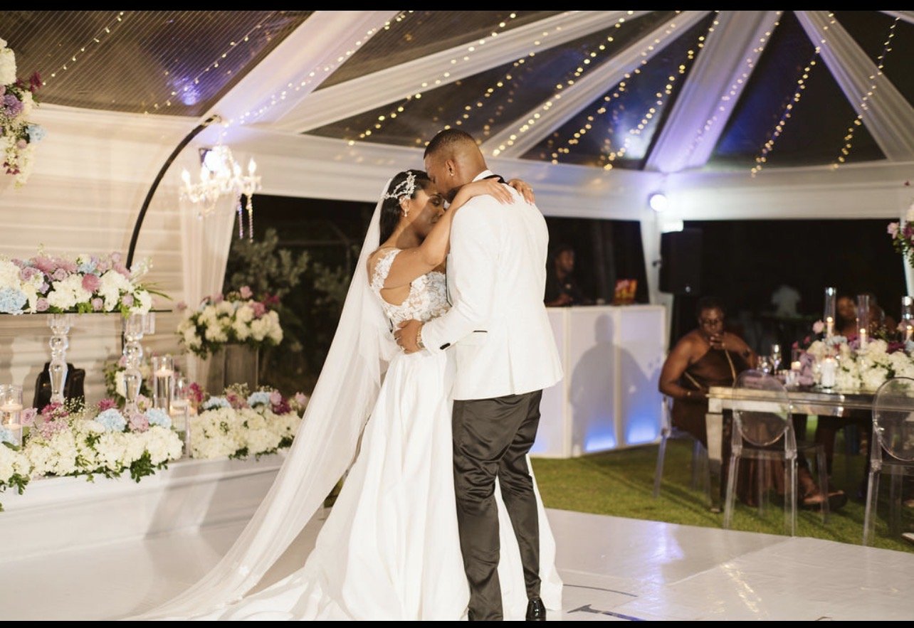 Bride and groom sharing a romantic dance at an elegant wedding reception under string lights.