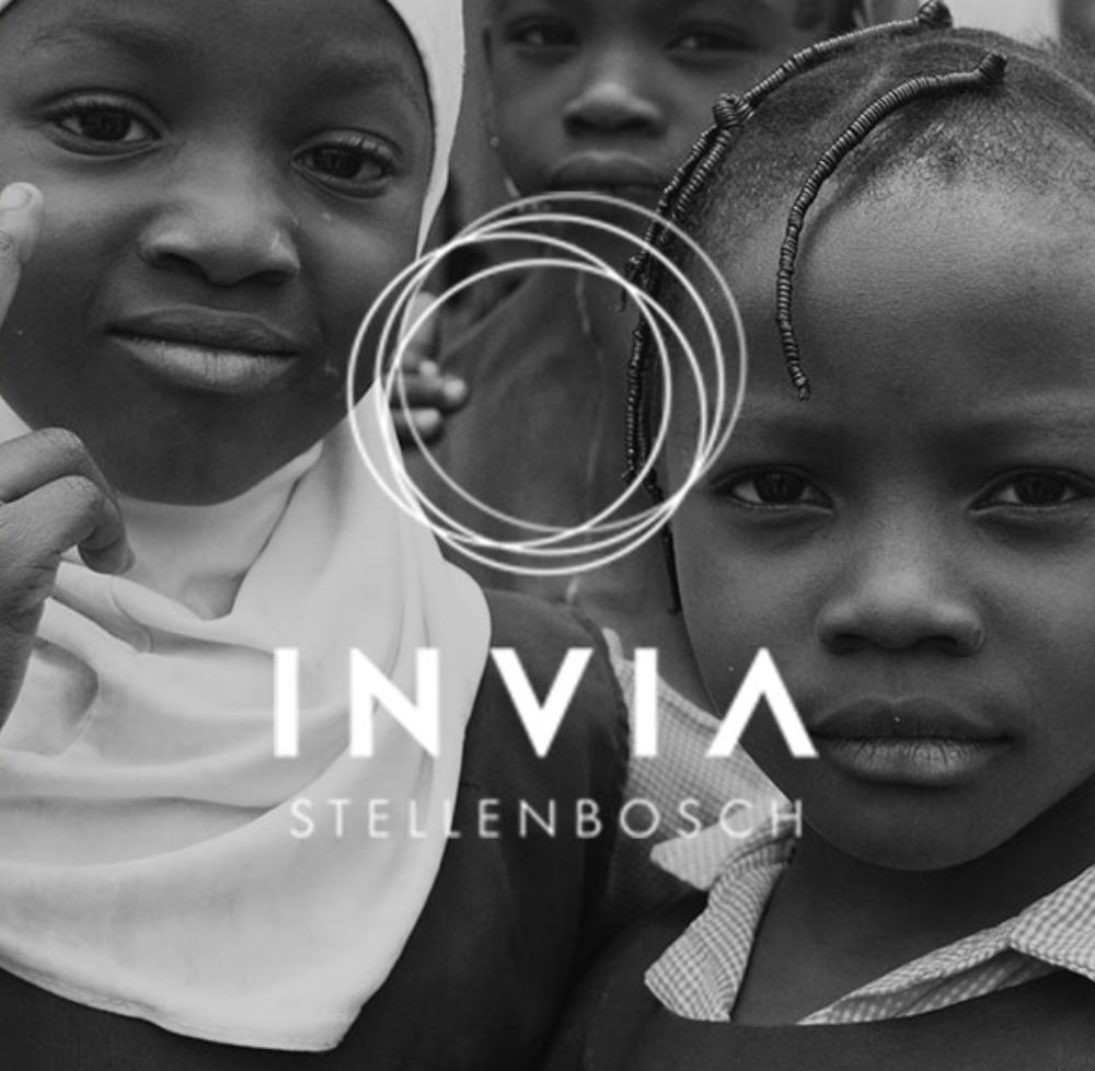 Three children, two girls and one boy, with serious expressions, close-up in black and white, with the word 'INVIYA' and 'STELLENBOSCH' overlayed on the image.