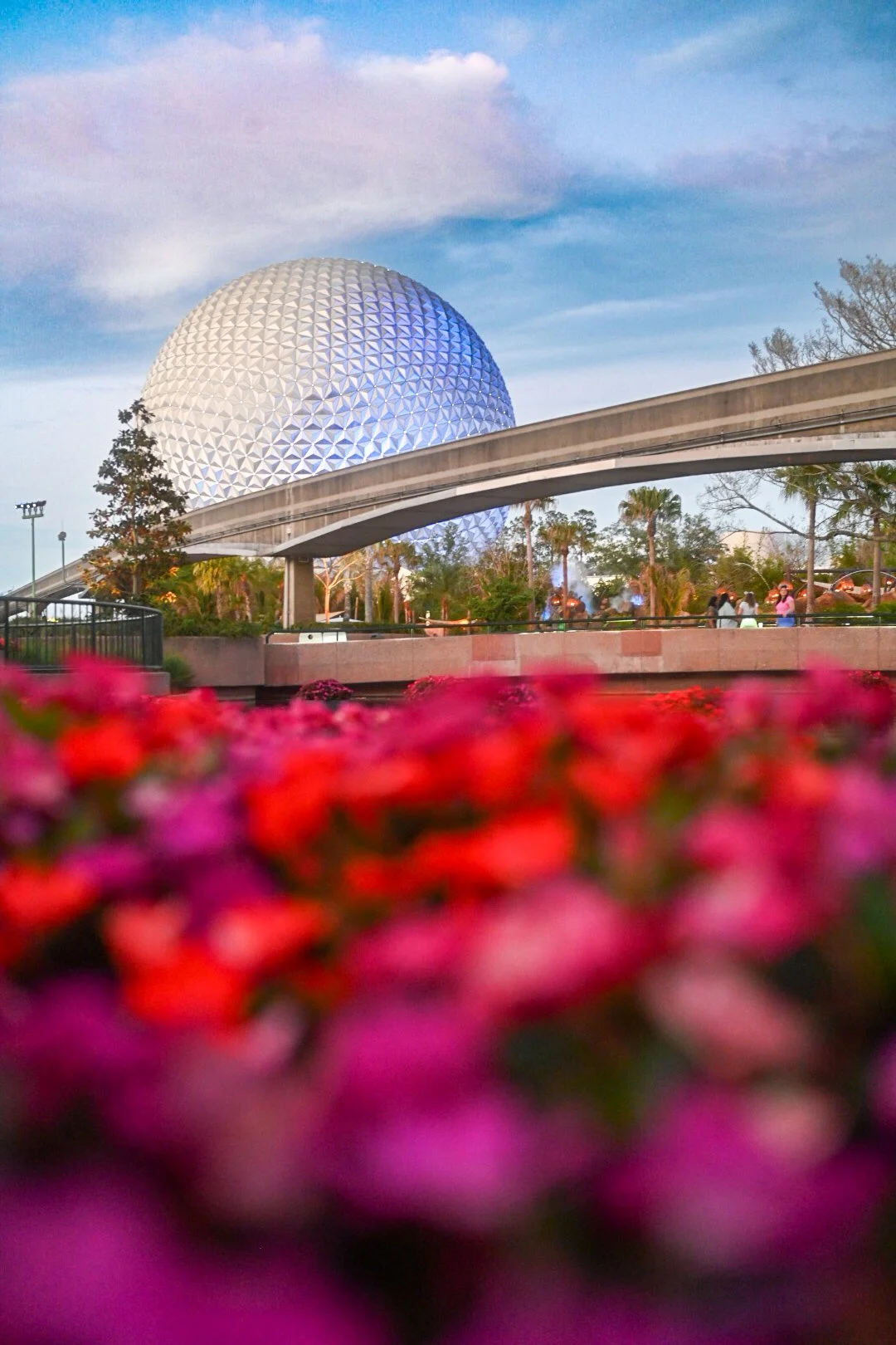 Icons of the Epcot geodesic sphere at Walt Disney World in Orlando, Florida, with pink and purple flowers in the foreground.