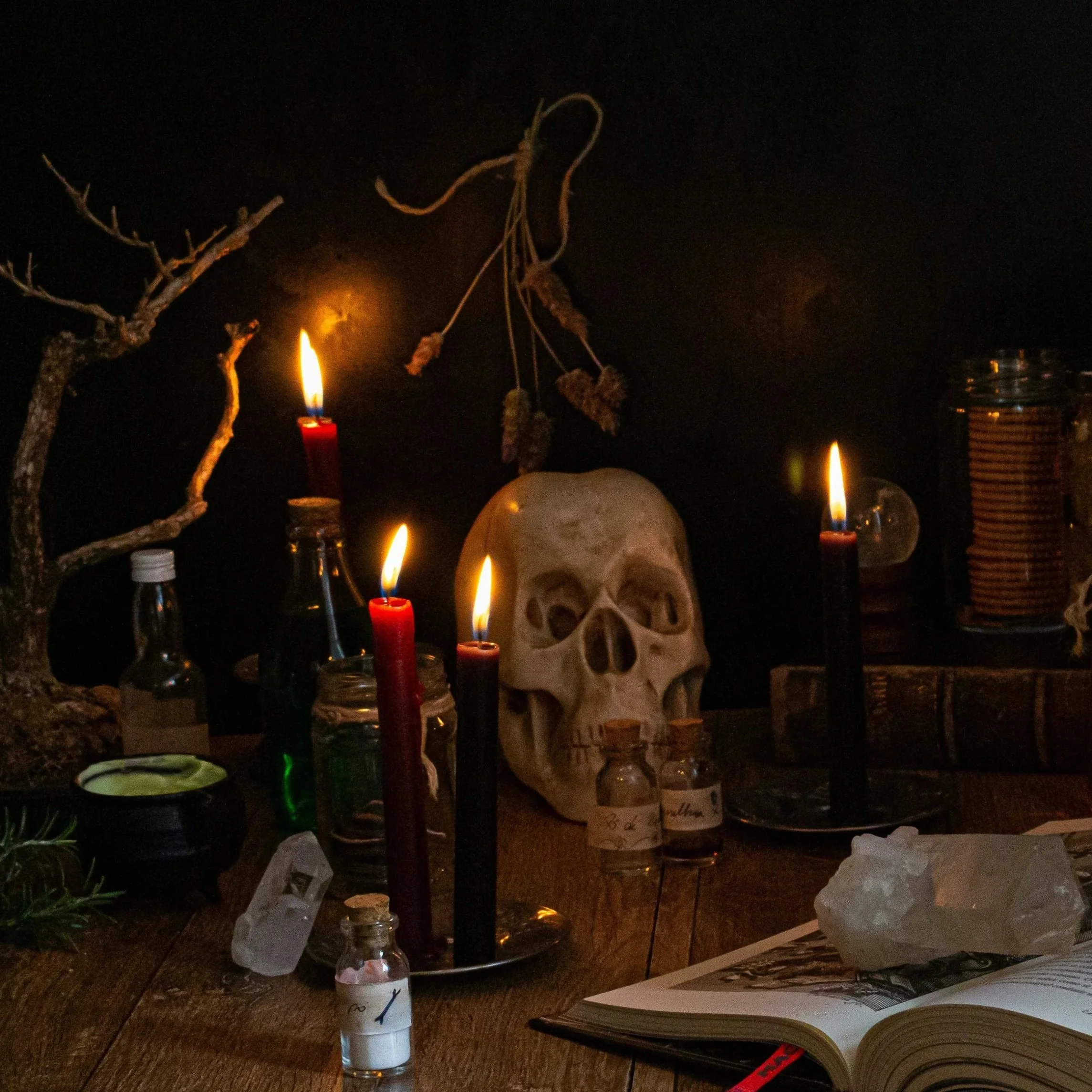 Ein dunkler Altar mit brennenden Kerzen, einer Tiermaske oder Schädel, einem Buch und einigen Dekorationen, die für eine Zeremonie oder eine Feier im Zusammenhang mit Totenkulten oder Halloween stehen.