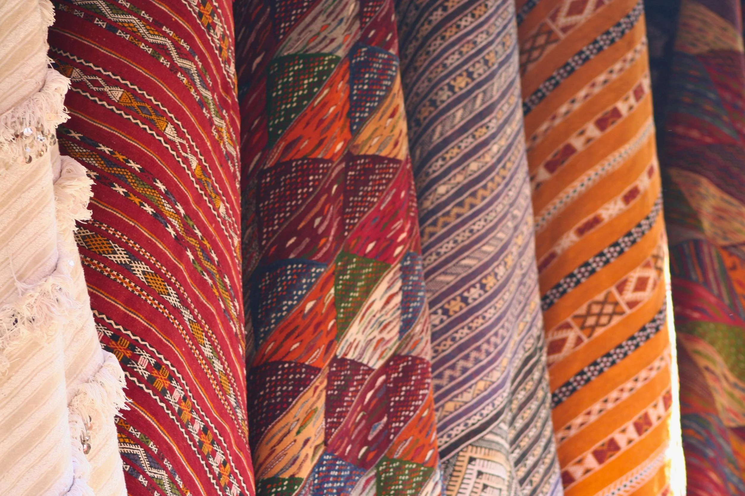 Close-up view of colorful, patterned fabric with traditional geometric designs in shades of red, orange, yellow, green, blue, and white.