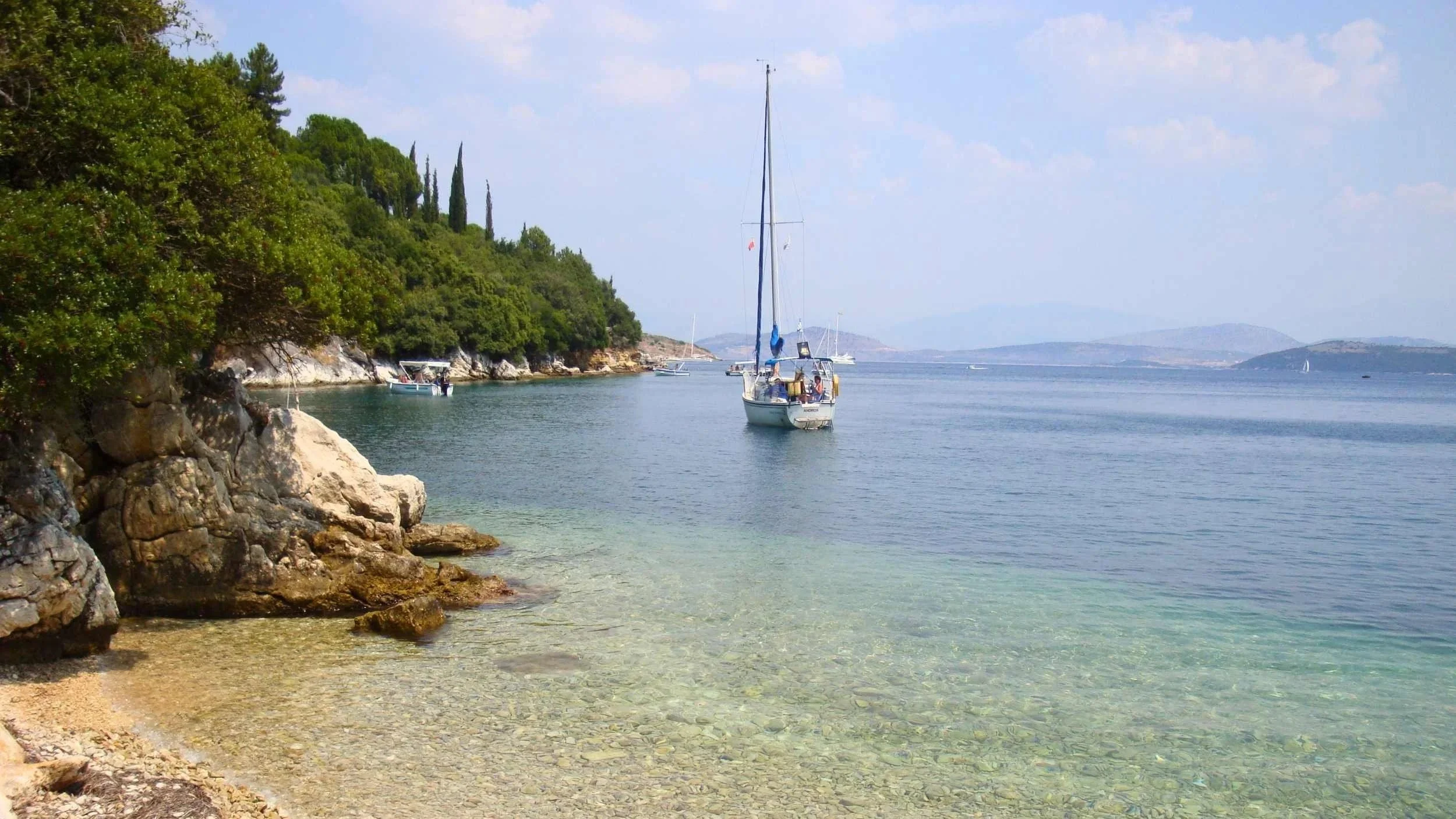 Beautiful quiet beach off the North East coast of Corfu with sailing boat