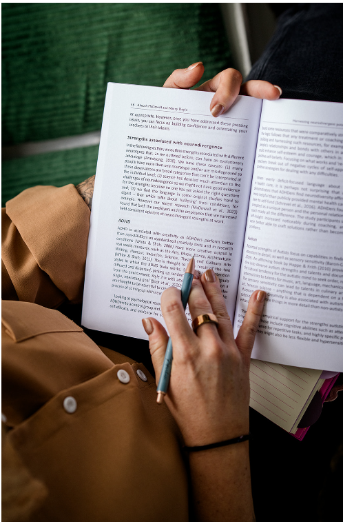 Person reading a printed document and holding a pen, with a green background.