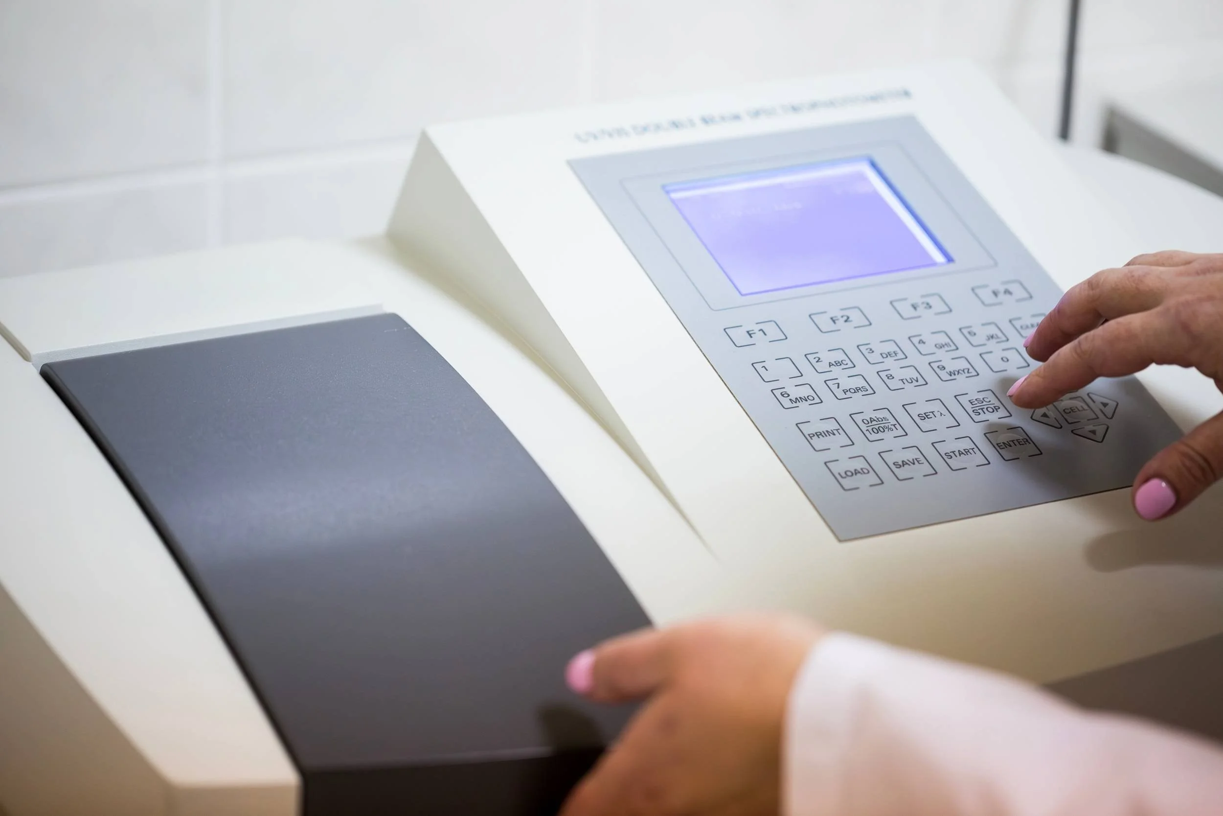 Person using a white security or access control keypad with a small screen and numeric buttons.
