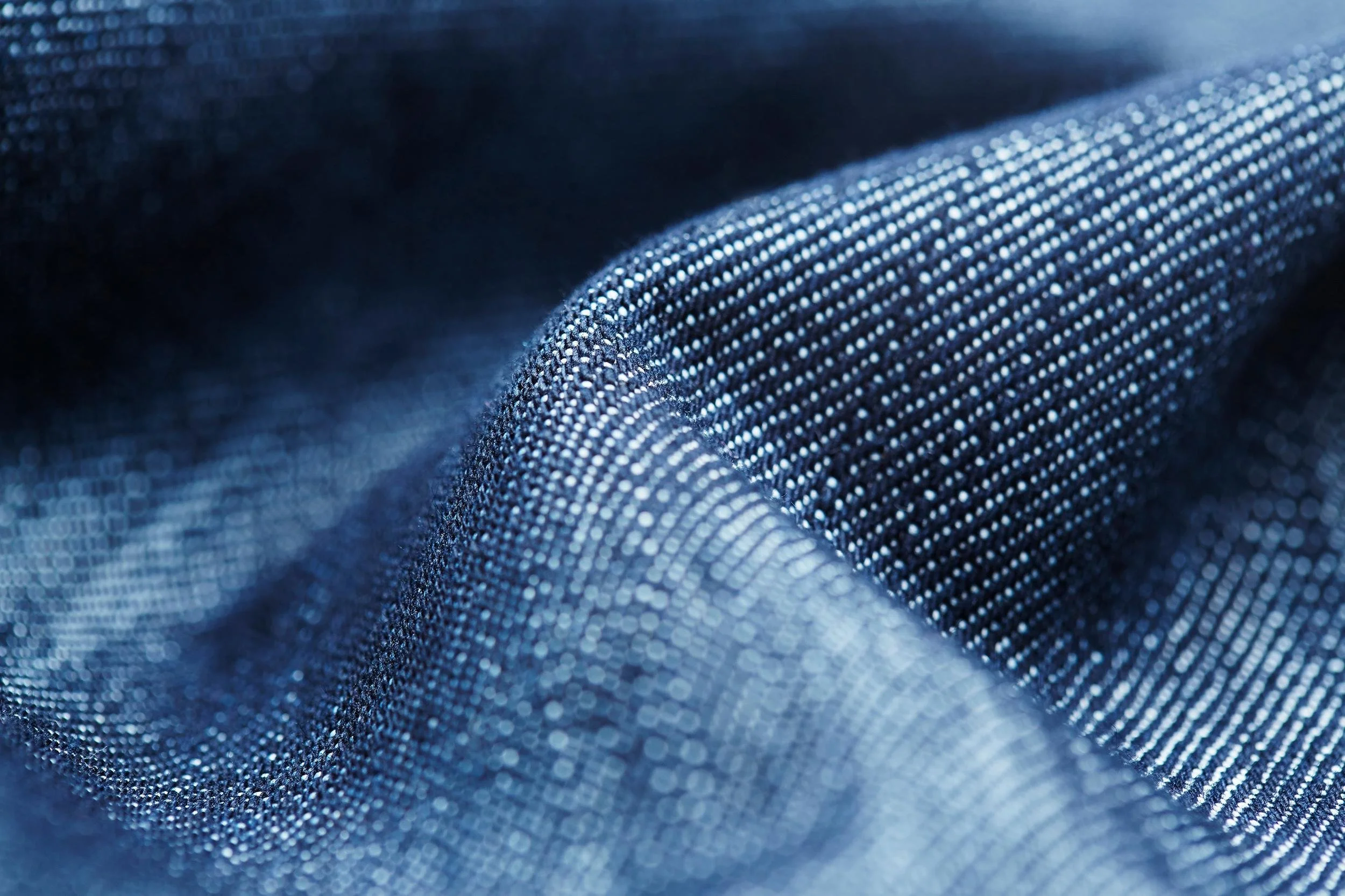 Close-up of blue fabric with a textured, dotted pattern and a wavy surface.