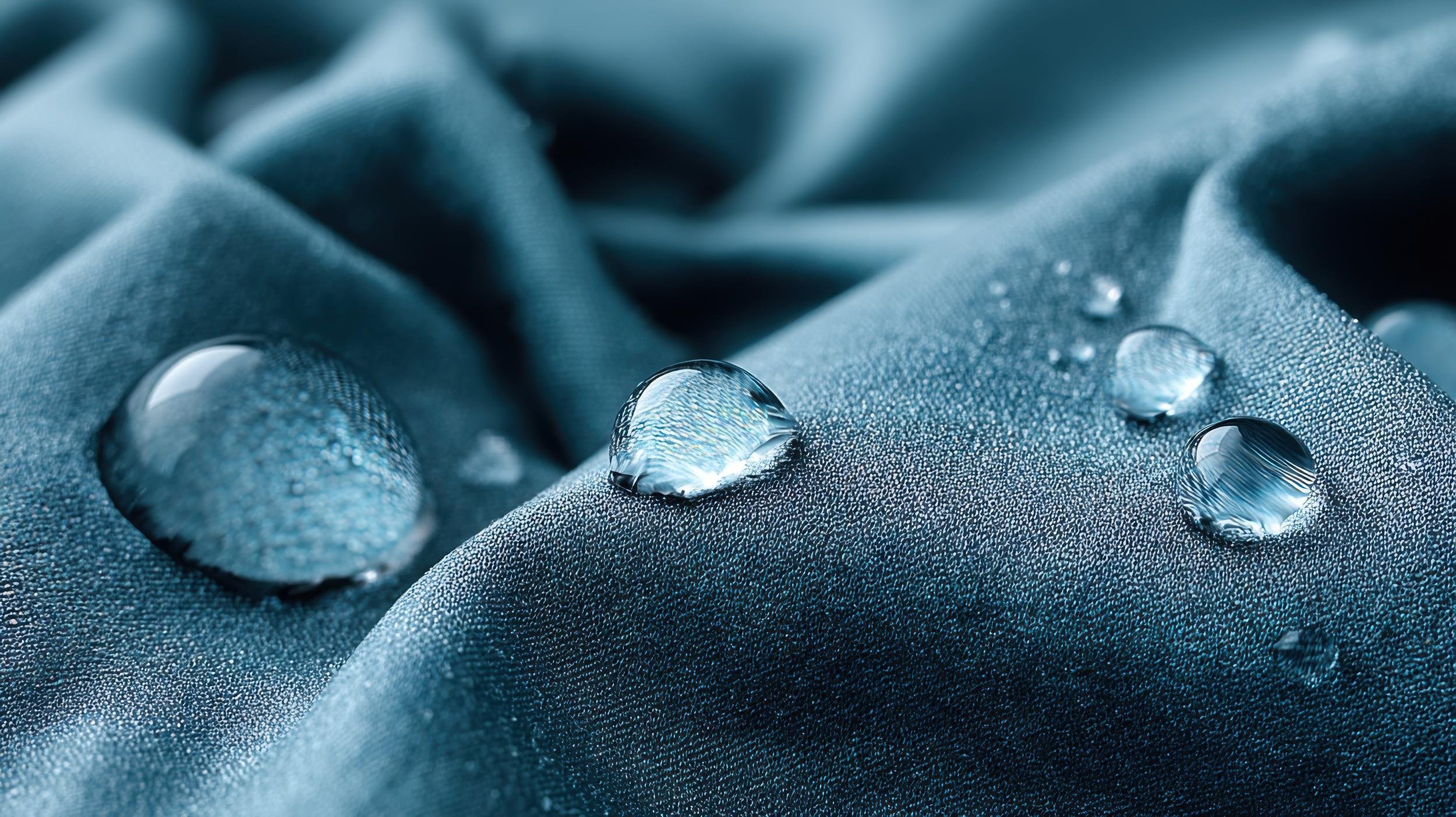 Close-up image of a textured blue fabric with water droplets on its surface.