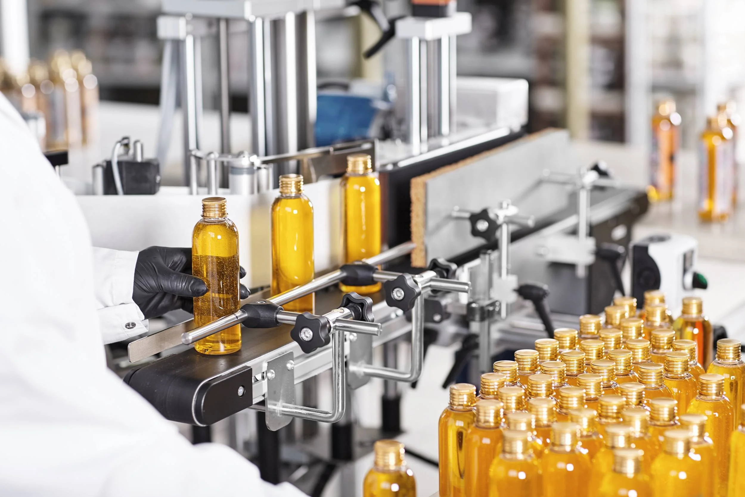 Automated production line filling amber bottles with liquid in a factory setting.