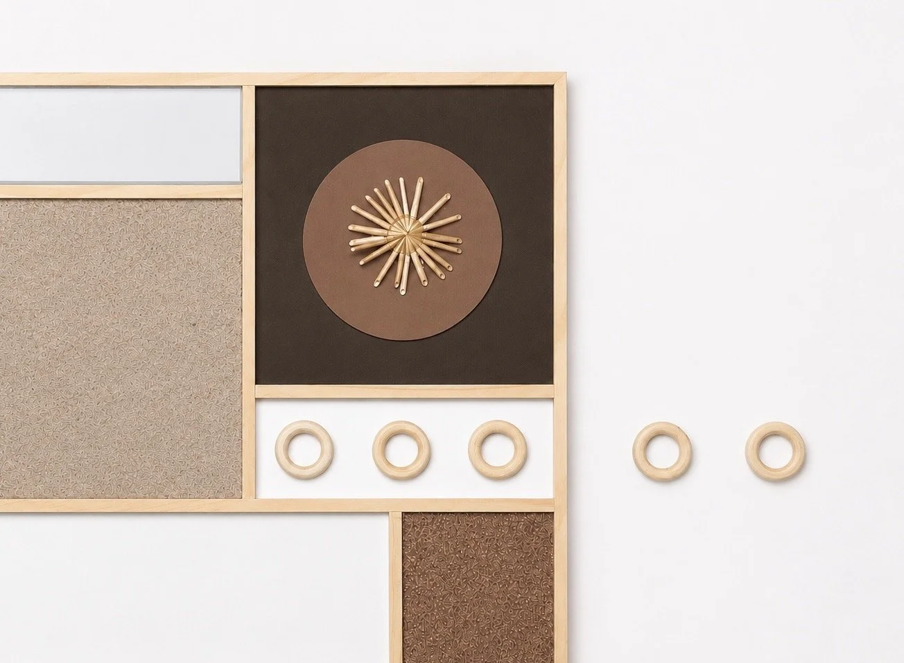 Modern wall decor with geometric wooden elements, including a clock with radiating spokes and three ring accents, mounted on a white wall.