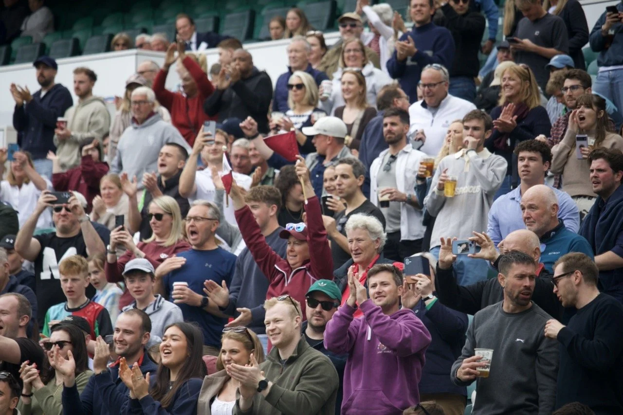 A supporter of Old Georgian's RFC raises her flags in the stands whilst supporting the team in the RFU Community Cup Semi Final