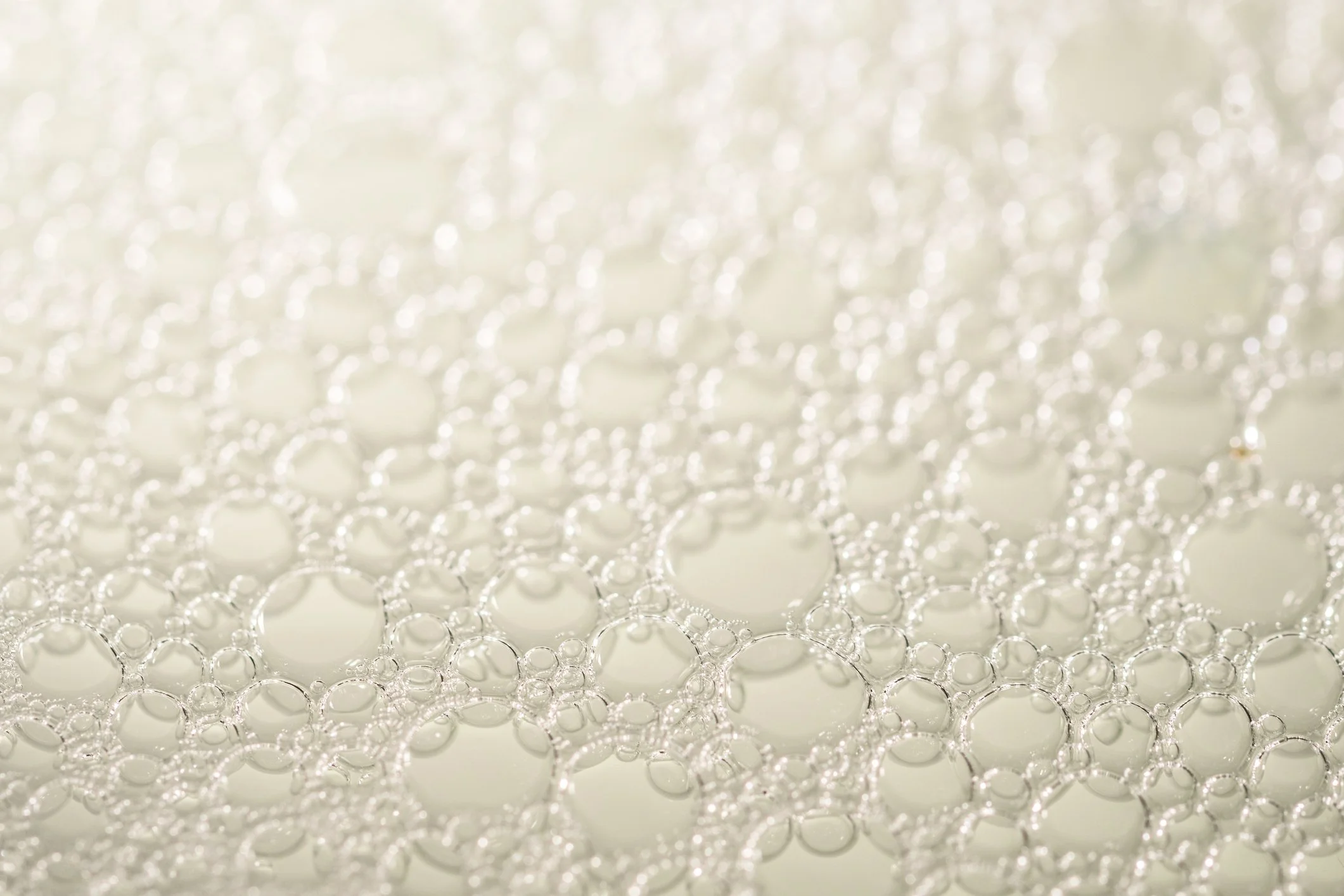 Close-up view of numerous transparent bubbles clustered together on a reflective surface.