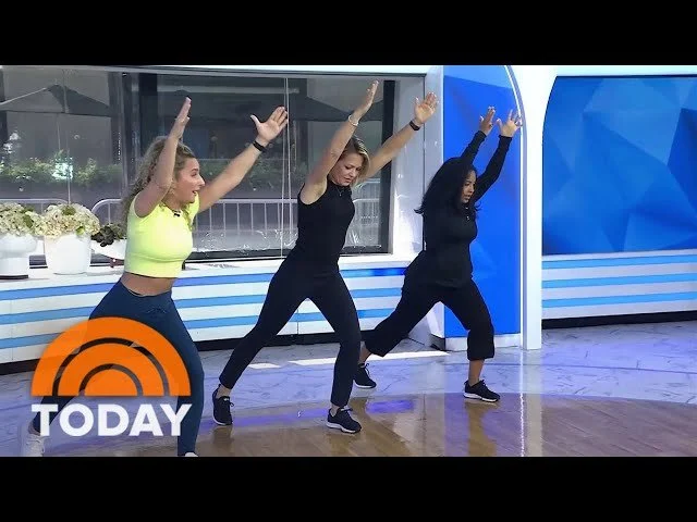 Three women performing a dance or exercise routine on a TV studio set with a "Today" logo in the corner, all with arms raised.