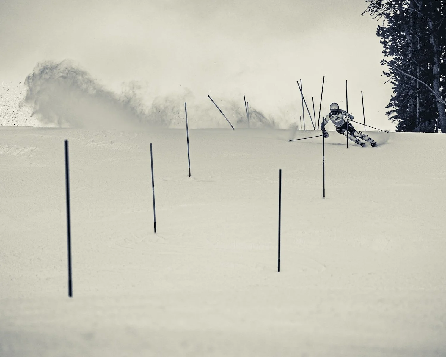 A skier wearing a helmet and racing suit navigates through slalom poles on a snow-covered slope during a ski race.
