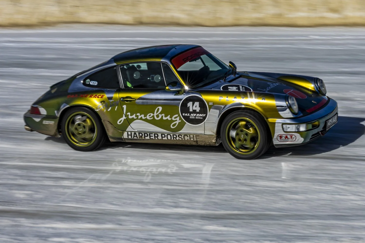 A race car speeding on a snowy track, decorated with green, black, and yellow colors, with the number 14 and various sponsor logos. F.A.T. ICE RACE 2026, Big Sky, Montana USA. Dan Lakatos Photo