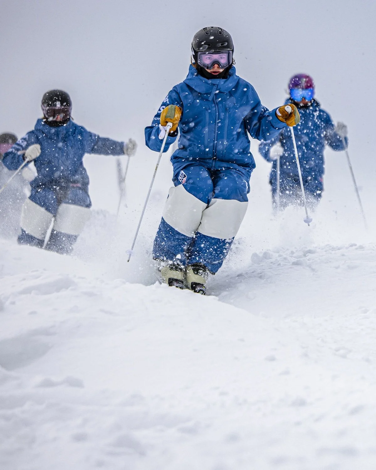 Children in winter gear skiing down a snow-covered slope