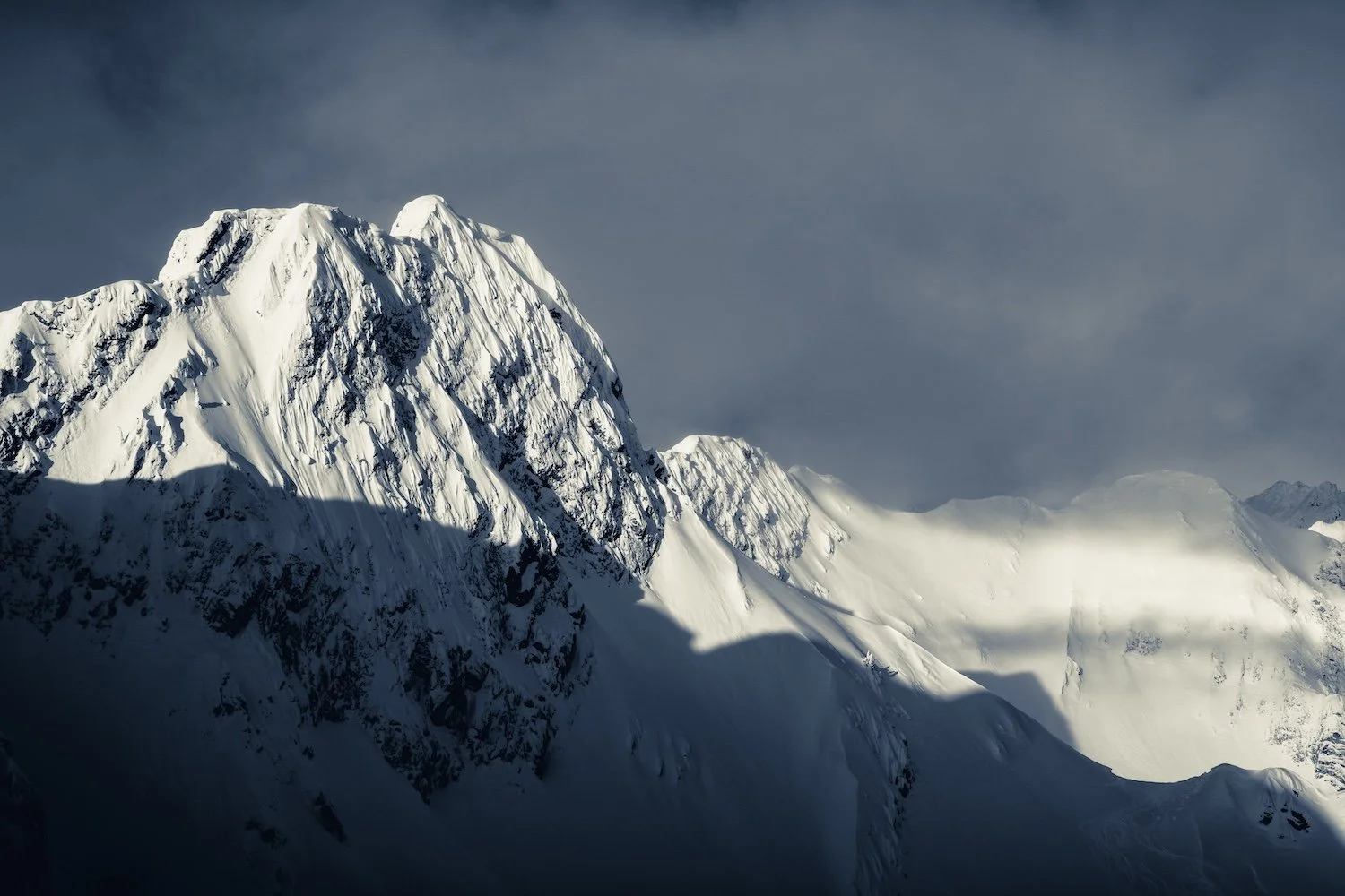 Snow-covered mountain range with steep peaks against a cloudy sky. Island Lake Lodge. Fernie, British Columbia, Canada