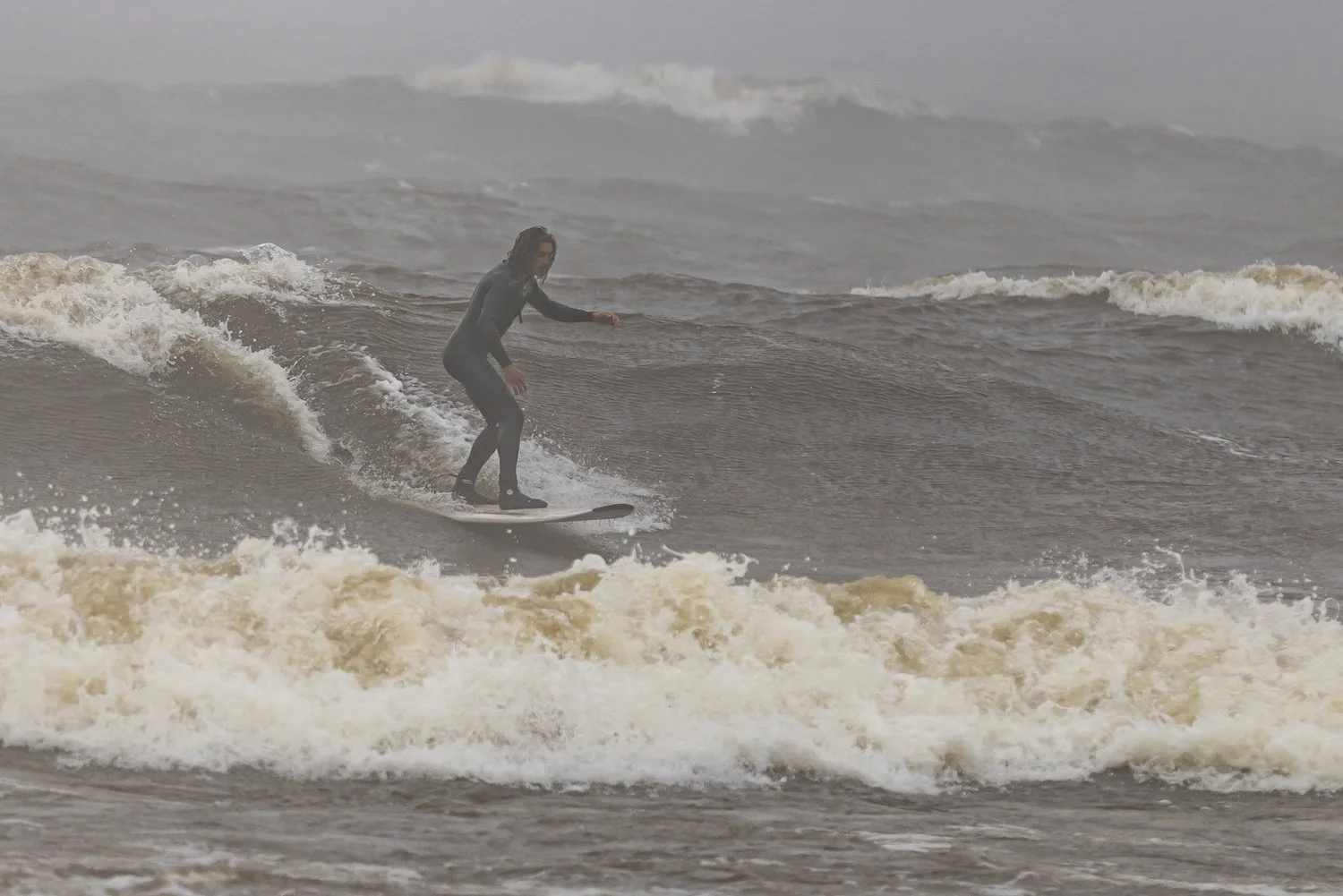 A person surfing on a wave in the ocean during overcast weather. Lake Superior, Duluth, MN