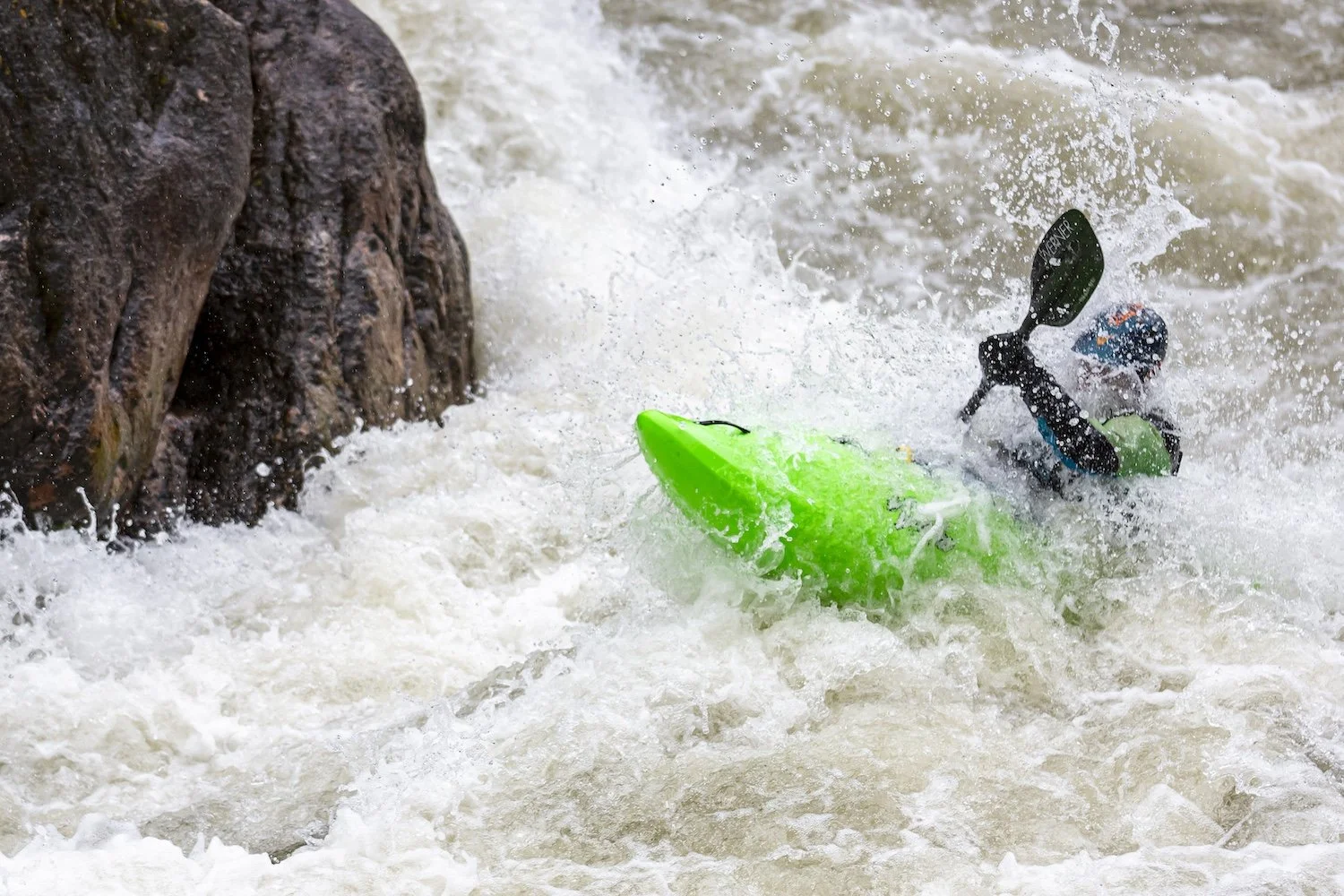 Person kayaking in white water rapids near rocks. Gallatin River, Montana, USA.